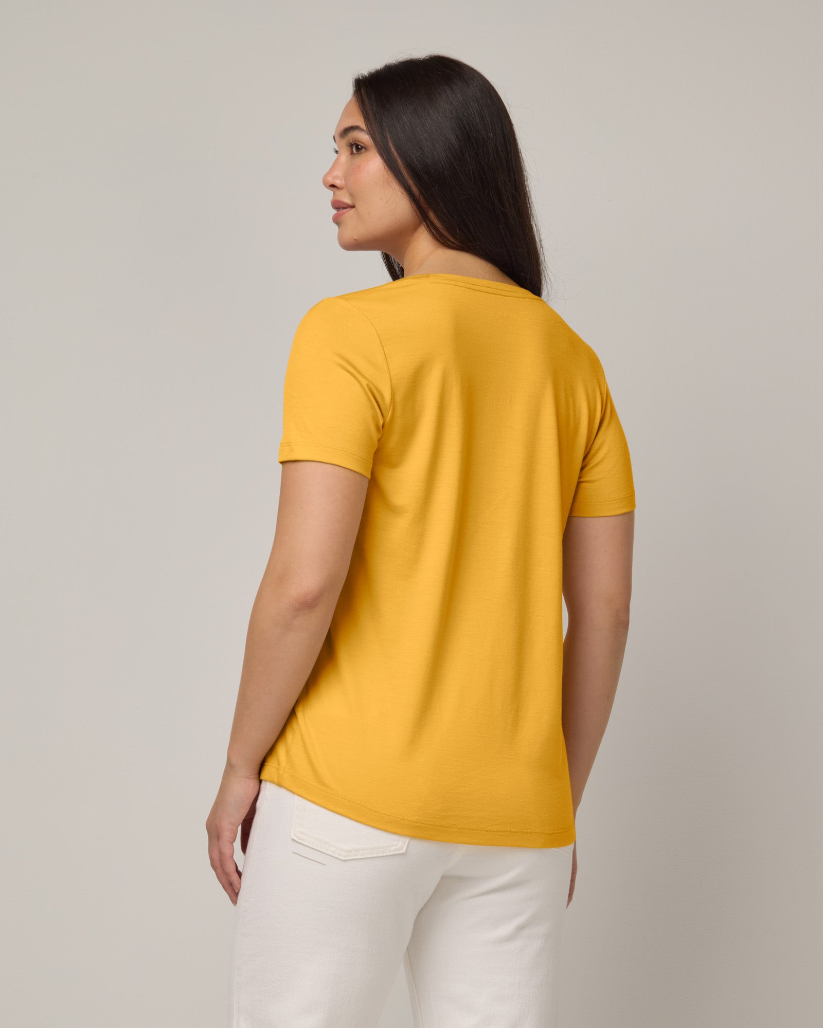 Model wearing Stella Scoop Neck Tee in Mango, a warm sunshine yellow color. Stella Scoop Neck Tee is a merino wool short sleeve, scoop neck t-shirt available in sizes XS-3X.