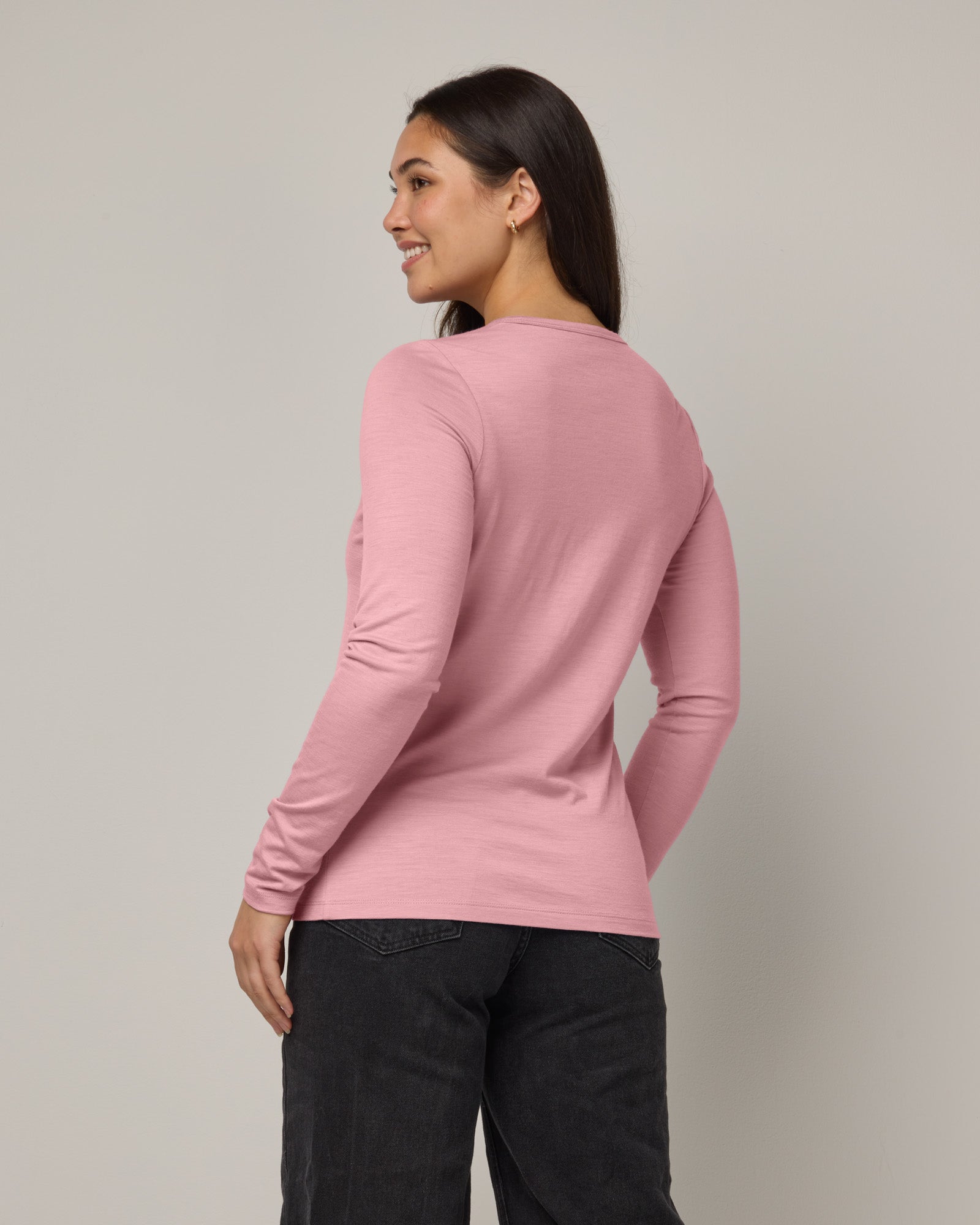 Model wearing Sloan 100% Fitted Tee in Ballet Pink, a baby light pink color. Sloan 100% Fitted Tee is a merino wool long sleeve, crew neck, slim fit tee available in sizes XS-3X.