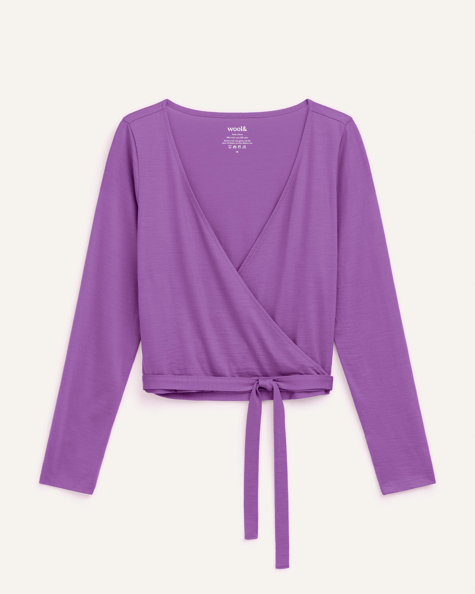 Laydown of Natalia Wrap Top in Purple Pansy, a bright, saturated purple color. Natalia Wrap Top is a merino wool long sleeve, v-neck, slim fit top available in sizes XS-3X.