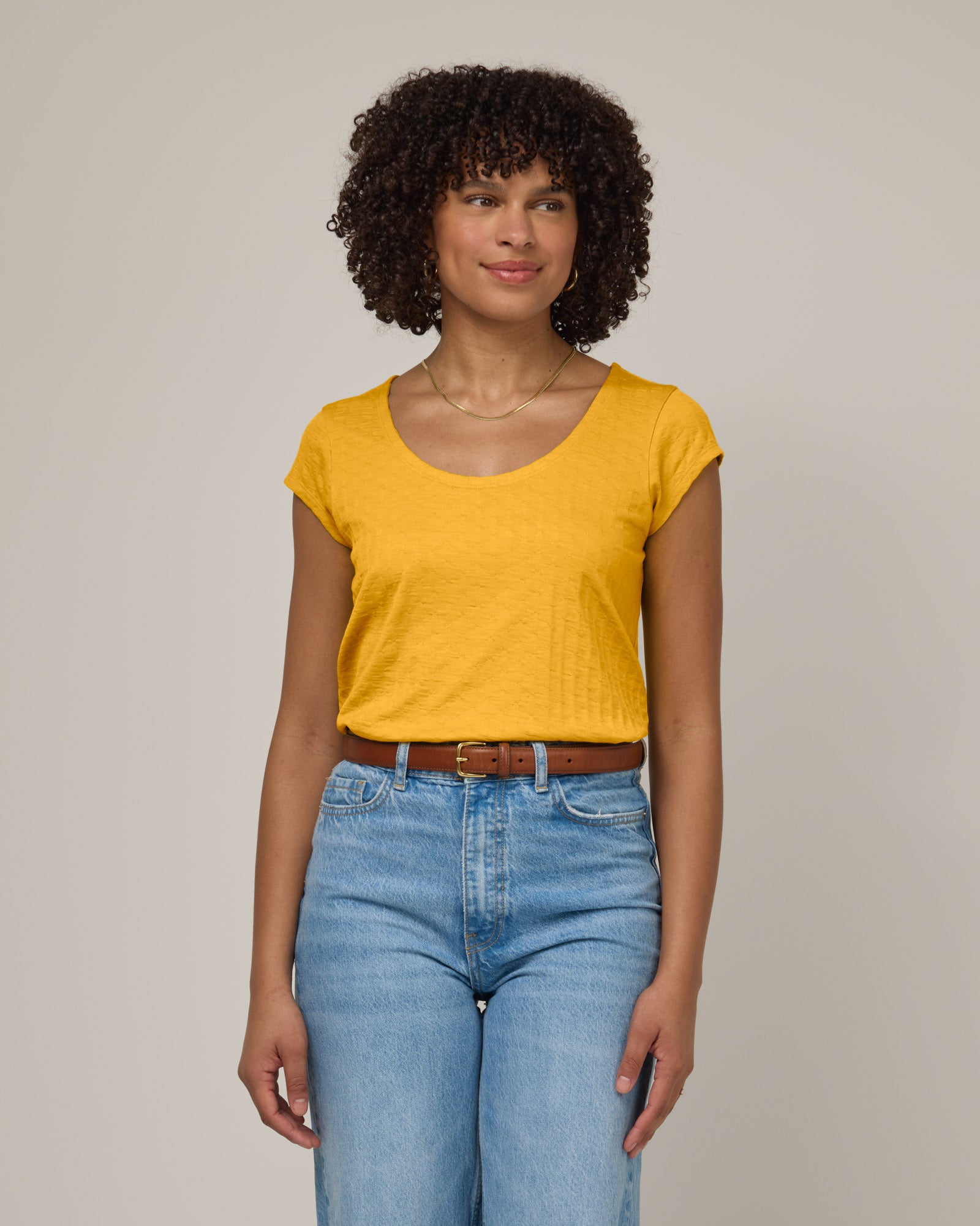 Model wearing Savanna Cap Sleeve Tee in Mango, a warm sunshine yellow color. Savanna Cap Sleeve Tee is a merino wool short sleeve, scoop neck, regular fit tee available in sizes XS-XXL.