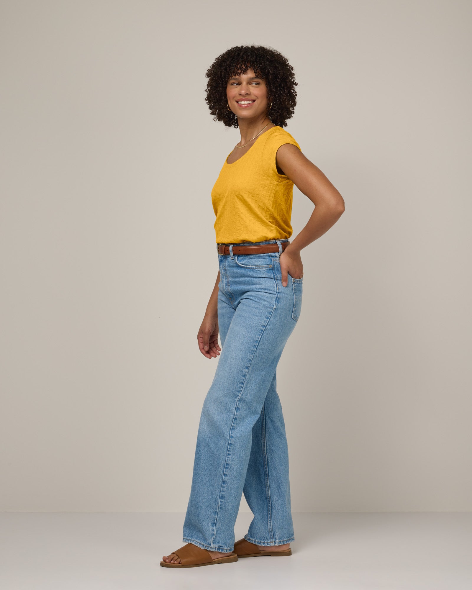 Model wearing Savanna Cap Sleeve Tee in Mango, a warm sunshine yellow color. Savanna Cap Sleeve Tee is a merino wool short sleeve, scoop neck, regular fit tee available in sizes XS-XXL.