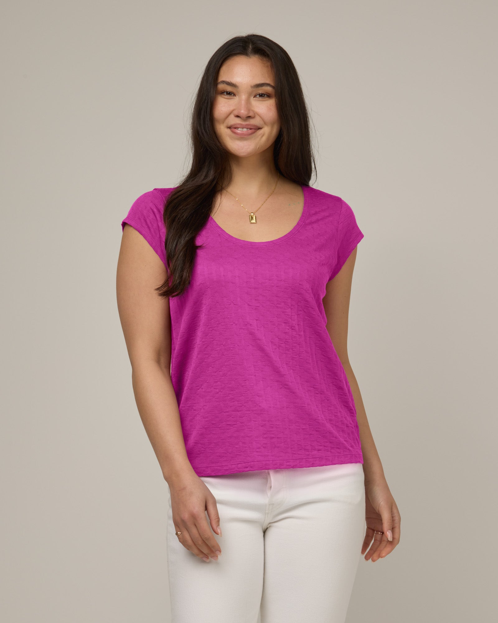 Model wearing Savanna Cap Sleeve Tee in Petunia, a bright fuchsia pink color. Savanna Cap Sleeve Tee is a merino wool short sleeve, scoop neck, regular fit tee available in sizes XS-XXL.