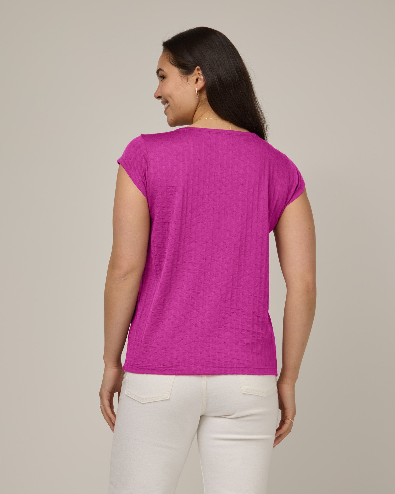Model wearing Savanna Cap Sleeve Tee in Petunia, a bright fuchsia pink color. Savanna Cap Sleeve Tee is a merino wool short sleeve, scoop neck, regular fit tee available in sizes XS-XXL.
