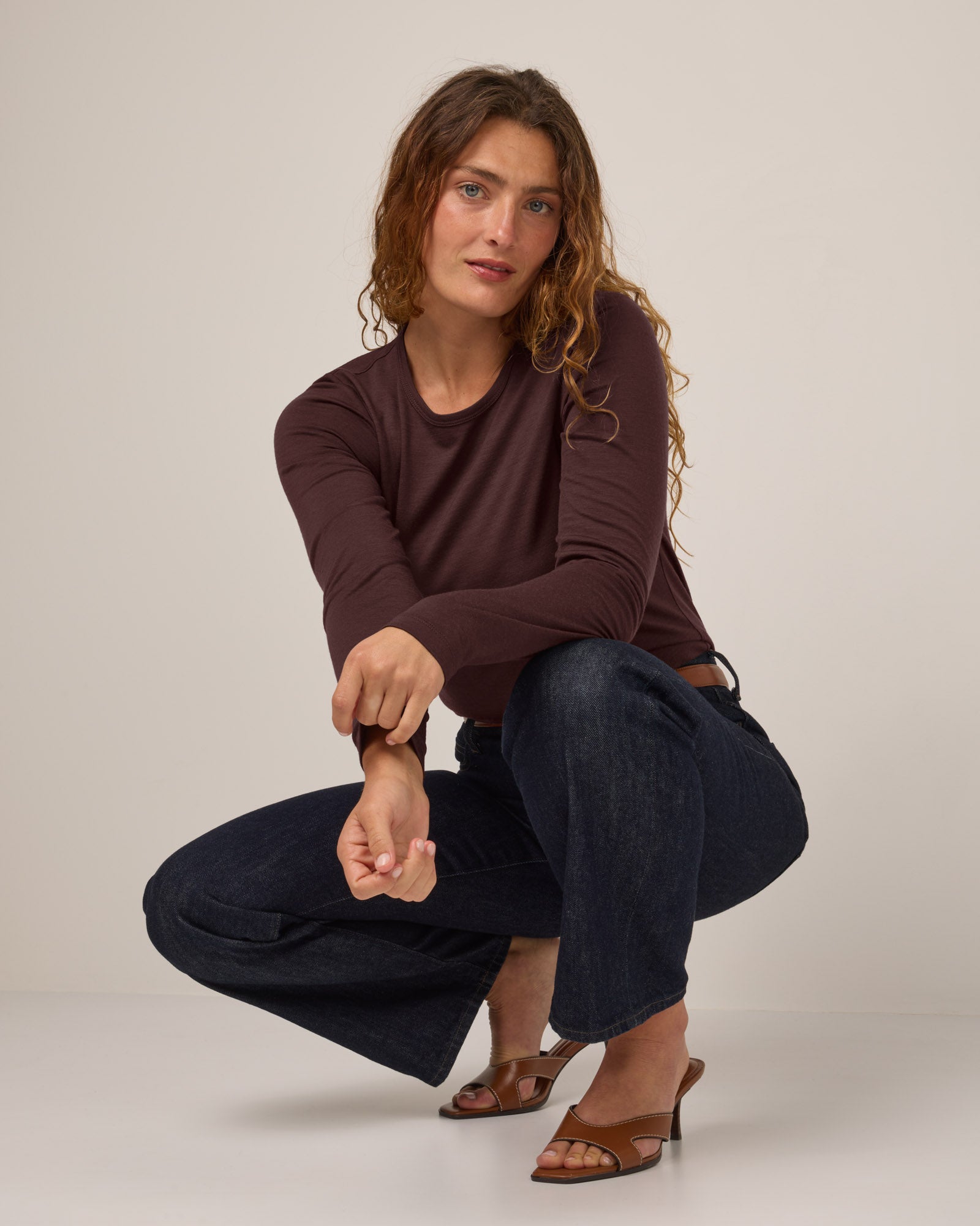 Model wearing Sloan 100% Fitted Tee in Espresso, a warm dark brown color. Sloan 100% Fitted Tee is a merino wool long sleeve, crew neck, slim fit tee available in sizes XS-3X.