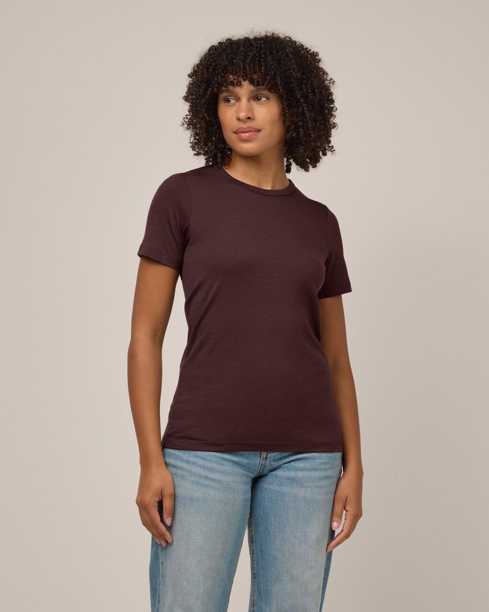 Model wearing Cara 100% Wool Fitted Tee in Espresso, a warm deep brown color. Cara 100% Wool Fitted Tee is a merino wool short sleeve, crew neck, slim fit tee available in sizes XS-3X.