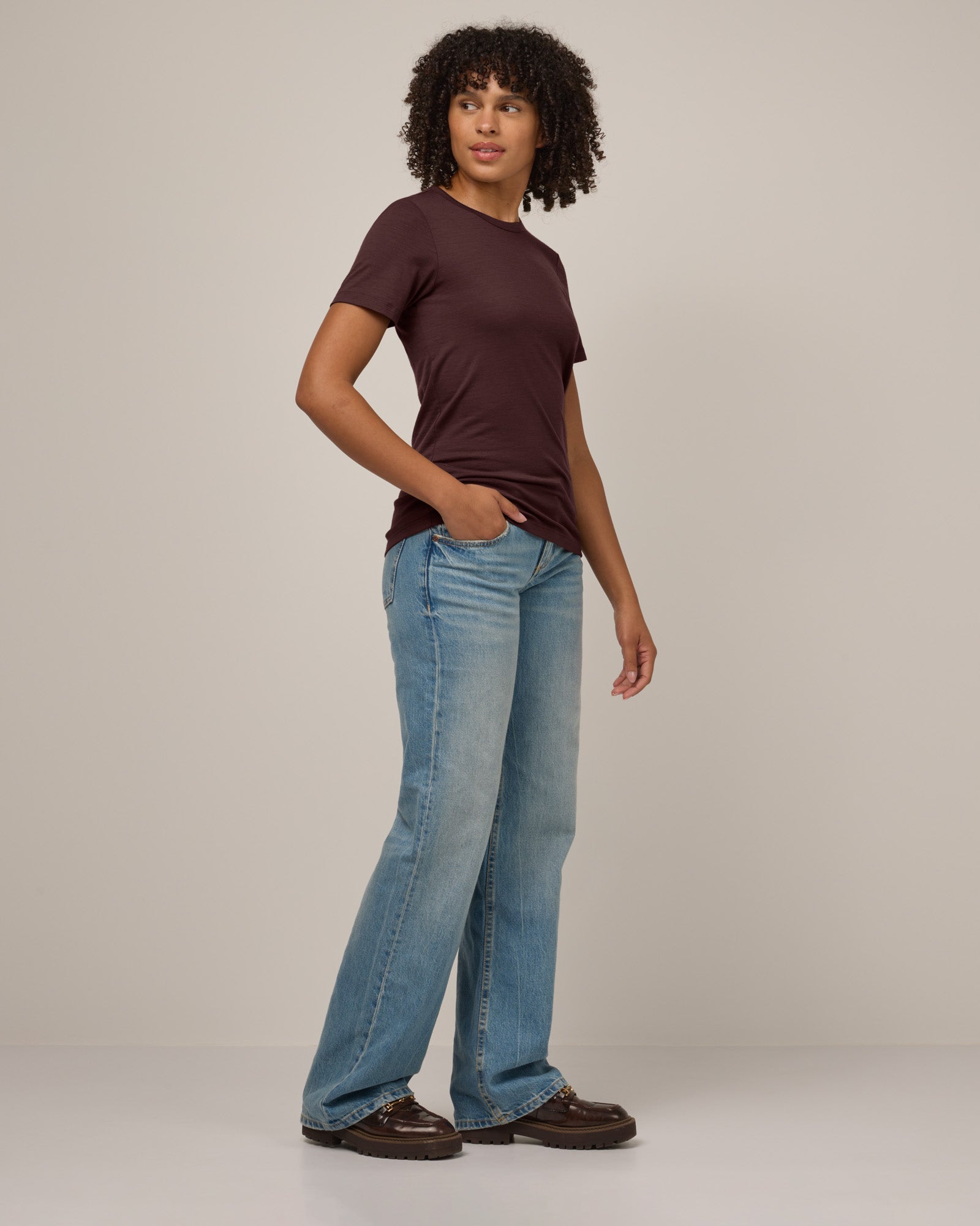 Model wearing Cara 100% Wool Fitted Tee in Espresso, a warm deep brown color. Cara 100% Wool Fitted Tee is a merino wool short sleeve, crew neck, slim fit tee available in sizes XS-3X.