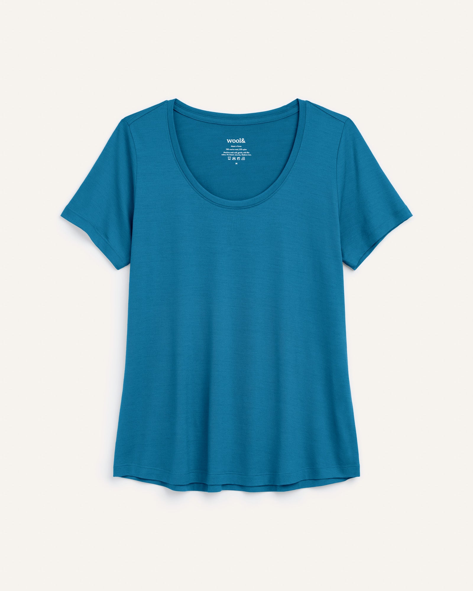 Laydown of Stella Signature Scoop Neck Tee in Ocean Teal, a medium blue-green color. Stella Signature Scoop Neck Tee is a merino wool short sleeve, scoop neck, relaxed fit tee available in sizes XS-3X.