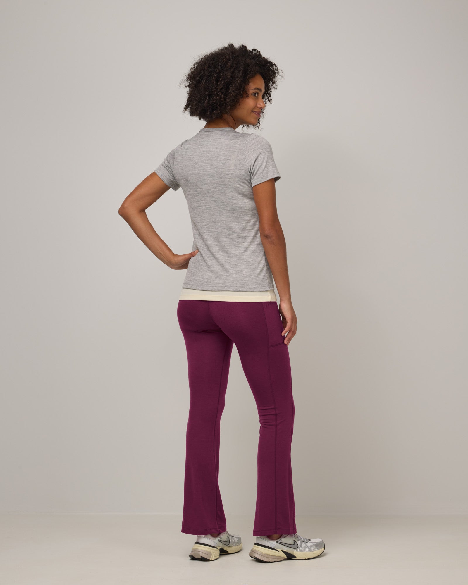 Model wearing Summit Straight Cut Pocket Legging in Plum, a purplish-red color. Summit Straight Cut Pocket Legging is a merino wool legging with pockets available in sizes XS-3X Regular, S-XXL Long.