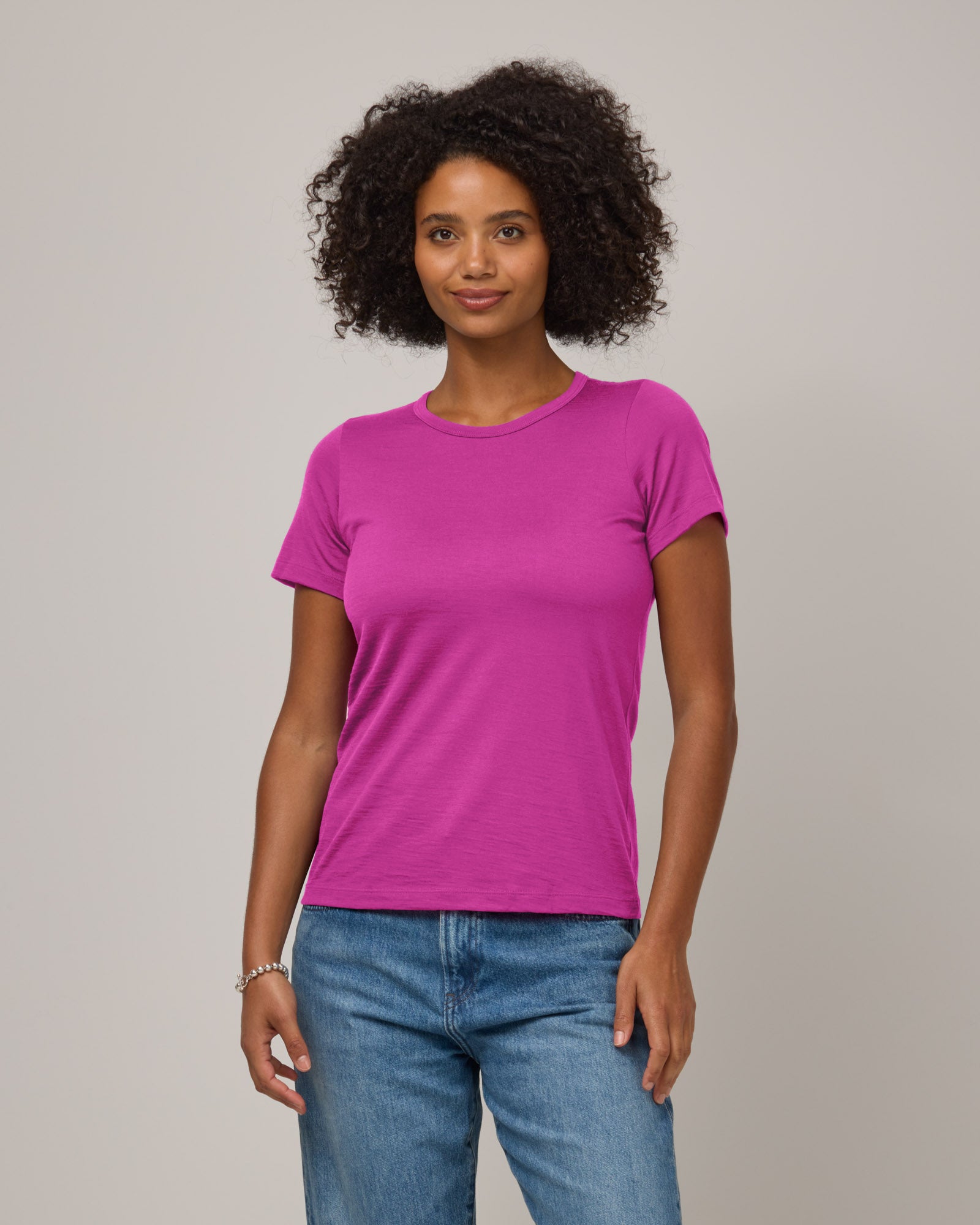 Model wearing Cara Signature Fitted Tee in Petunia, a bright fuchsia pink color. Cara Signature Fitted Tee is a merino wool short sleeve, crew neck, slim fit tee available in sizes XS-3X.