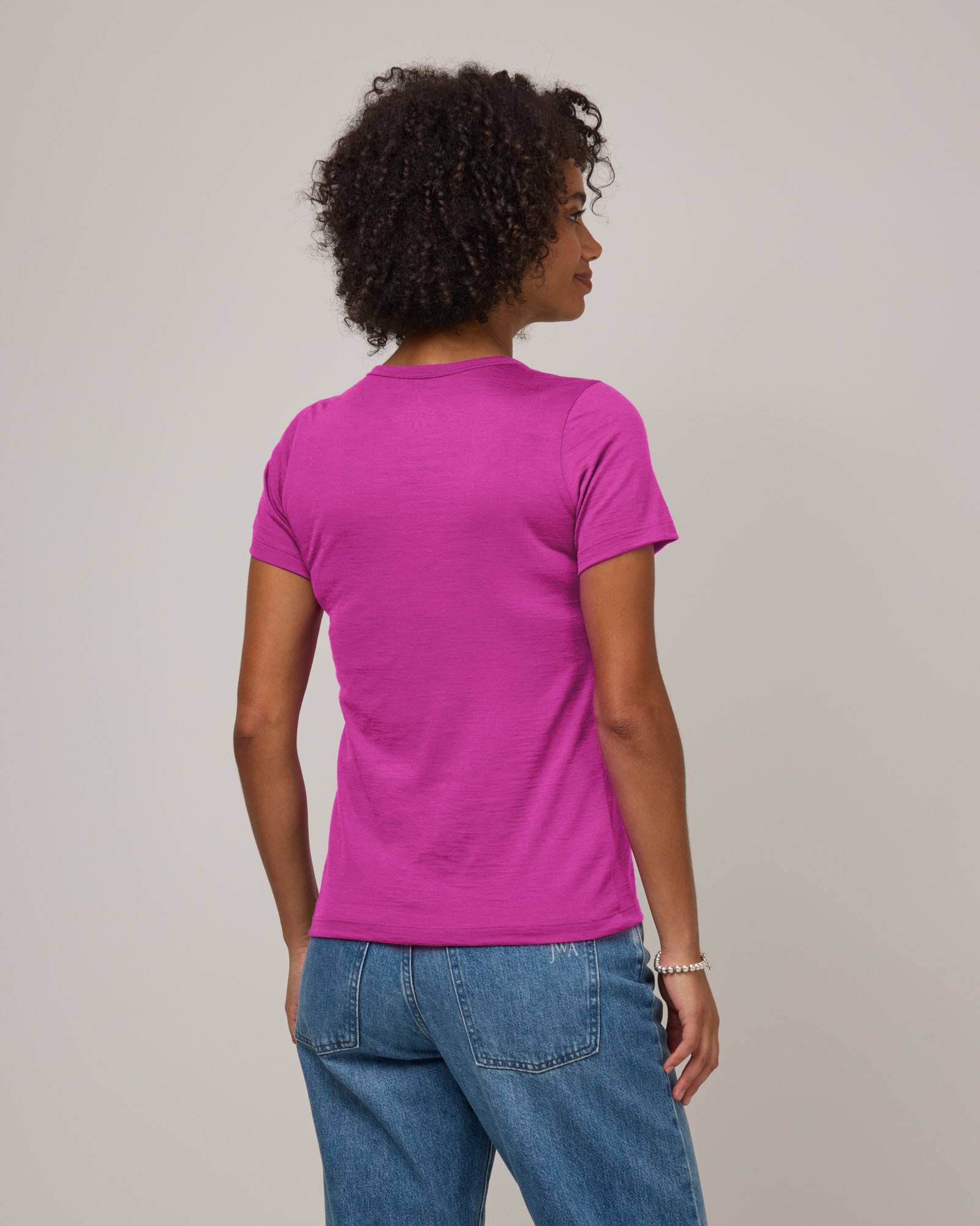 Model wearing Cara Signature Fitted Tee in Petunia, a bright fuchsia pink color. Cara Signature Fitted Tee is a merino wool short sleeve, crew neck, slim fit tee available in sizes XS-3X.