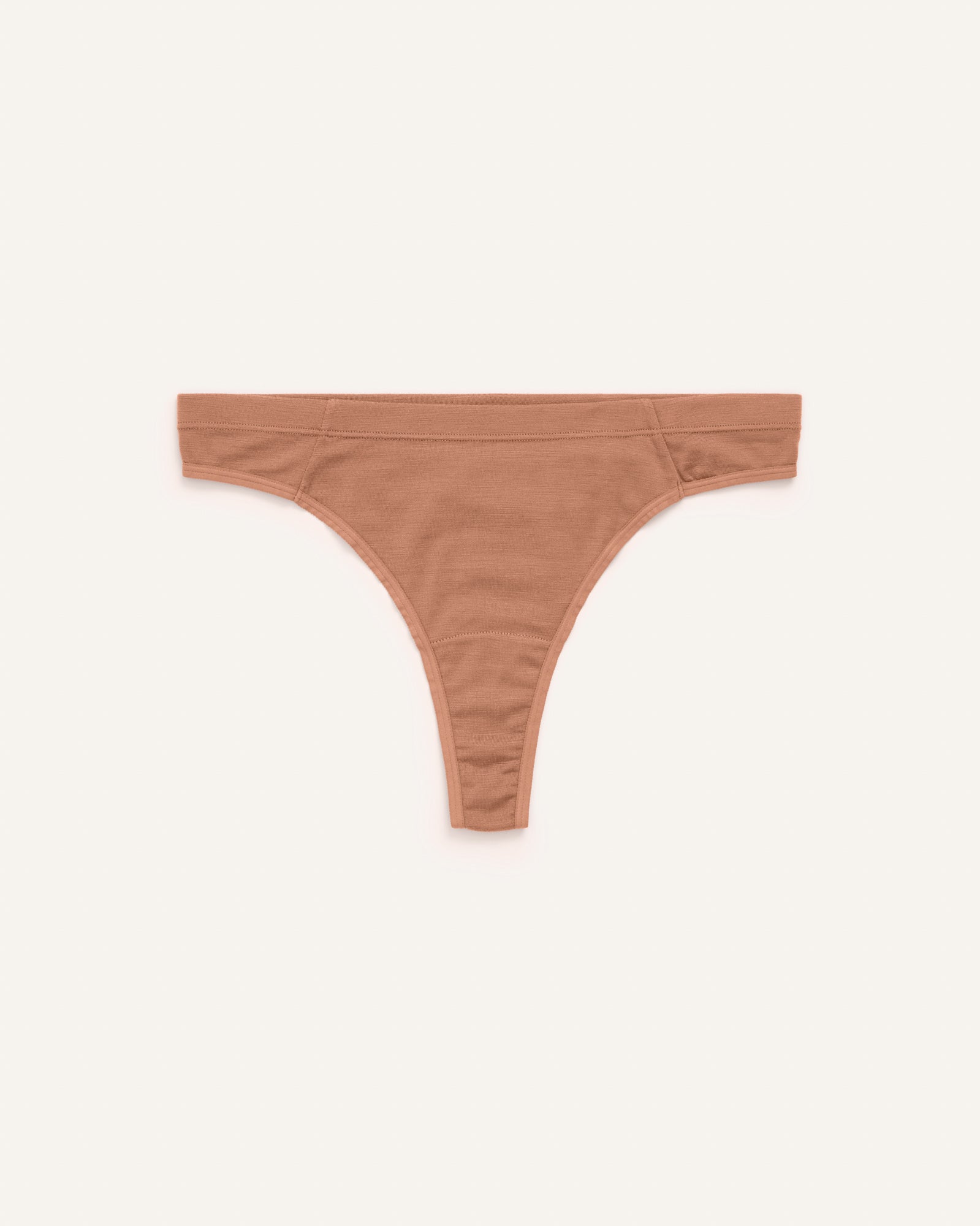 Laydown of Roam Thong in Mocha Brown, a medium-dark nude color. Roam Thong is a merino wool underwear available in sizes XS-3X
