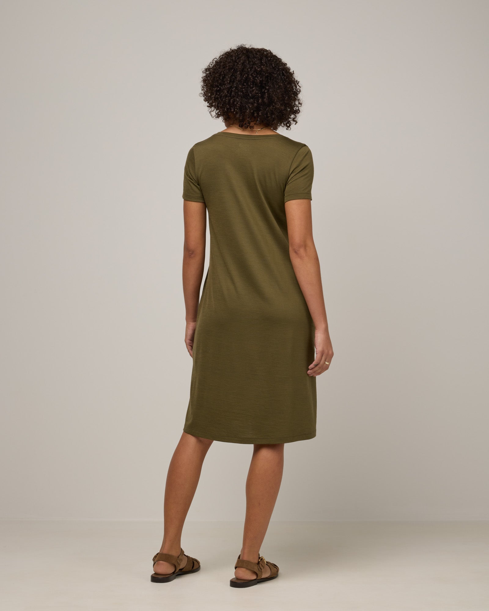 Model wearing Maggie Swing Dress in Olive. Maggie Swing Dress is a merino wool short sleeve, scoop neck, knee length swing dress with pockets available in sizes XS-3X Regular, XS-3X Long.