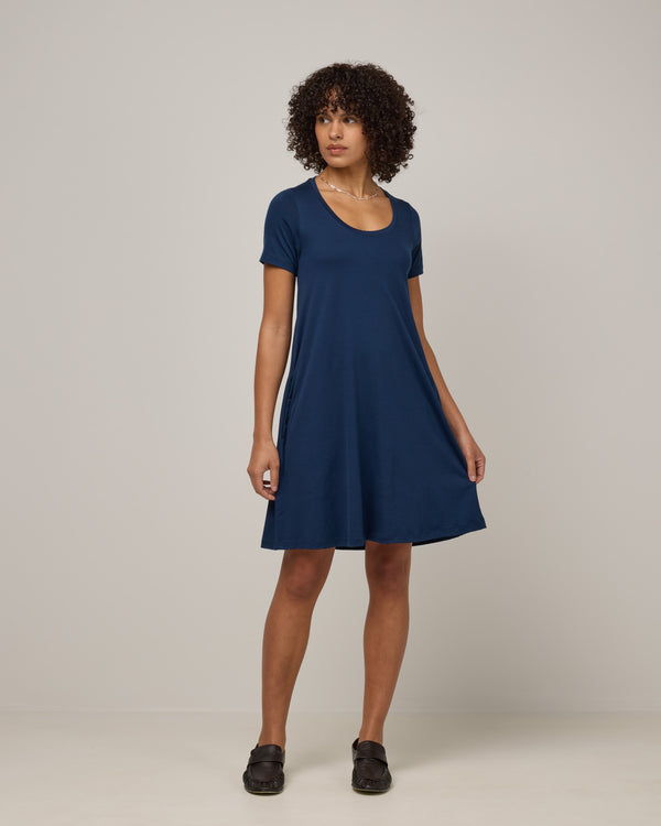 Model wearing Maggie Swing Dress in Marine Blue, a deep royal blue color. Maggie Swing Dress is a merino wool short sleeve, scoop neck, knee length swing dress with pockets available in sizes XS-3X Regular, XS-3X Long.