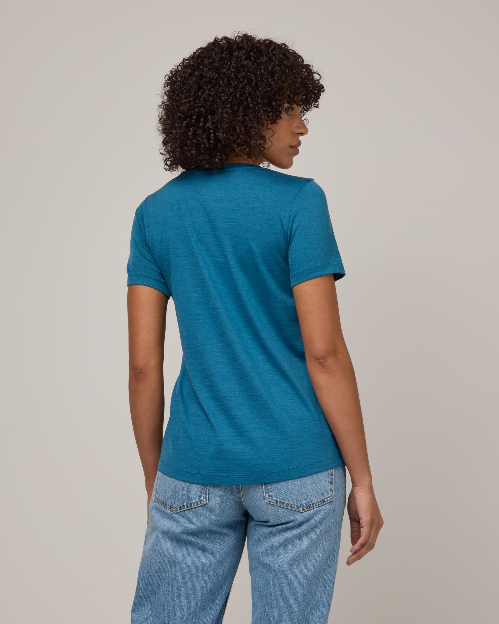 Model wearing Stella Signature Scoop Neck Tee in Ocean Teal, a medium blue-green color. Stella Signature Scoop Neck Tee is a merino wool short sleeve, scoop neck, relaxed fit tee available in sizes XS-3X.