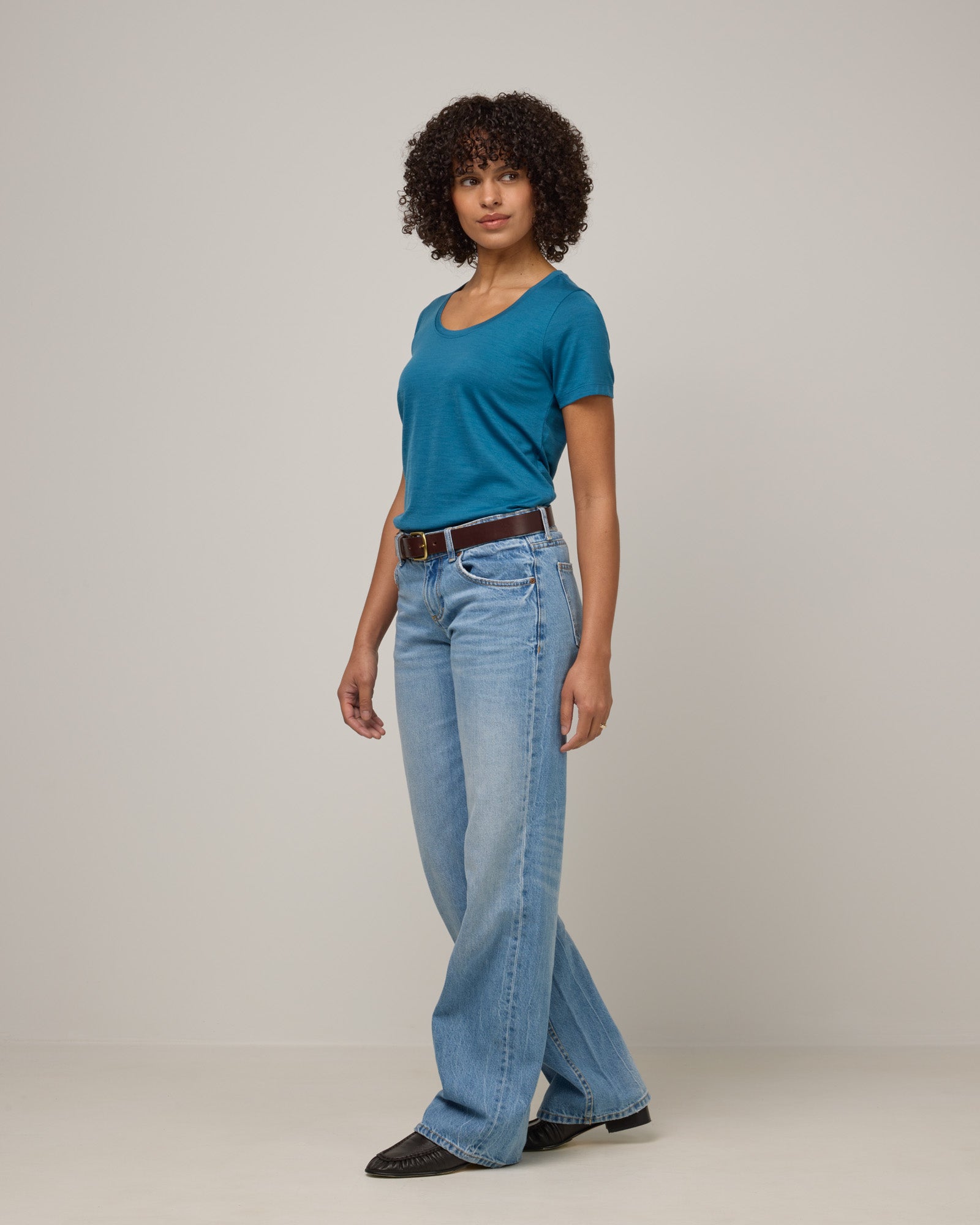 Model wearing Stella Signature Scoop Neck Tee in Ocean Teal, a medium blue-green color. Stella Signature Scoop Neck Tee is a merino wool short sleeve, scoop neck, relaxed fit tee available in sizes XS-3X.