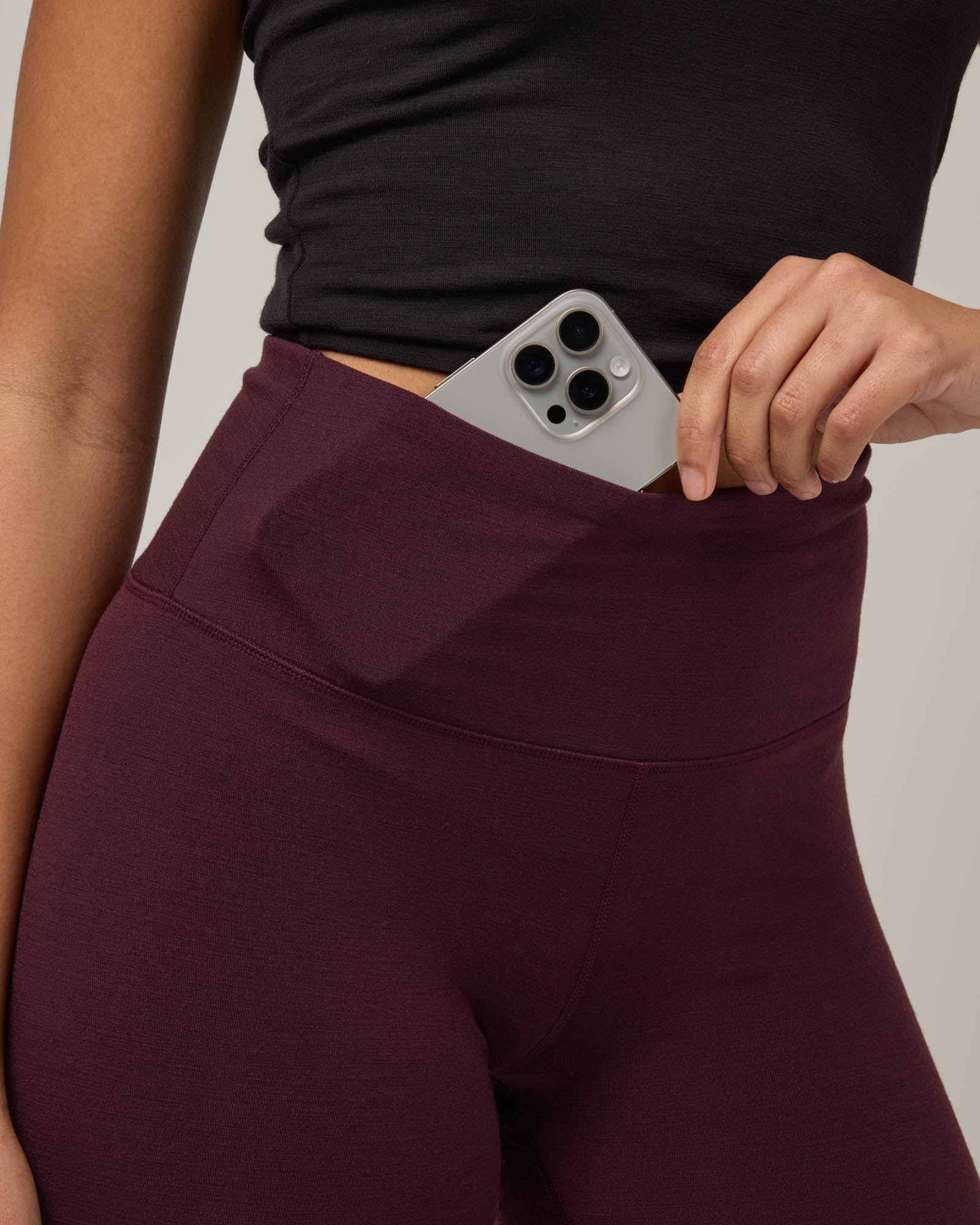 Model wearing Summit Legging in Dark Marionberry, a deep berry purple color. Summit Legging is a merino wool legging available in sizes XS-3X Regular, S-XXL Long.