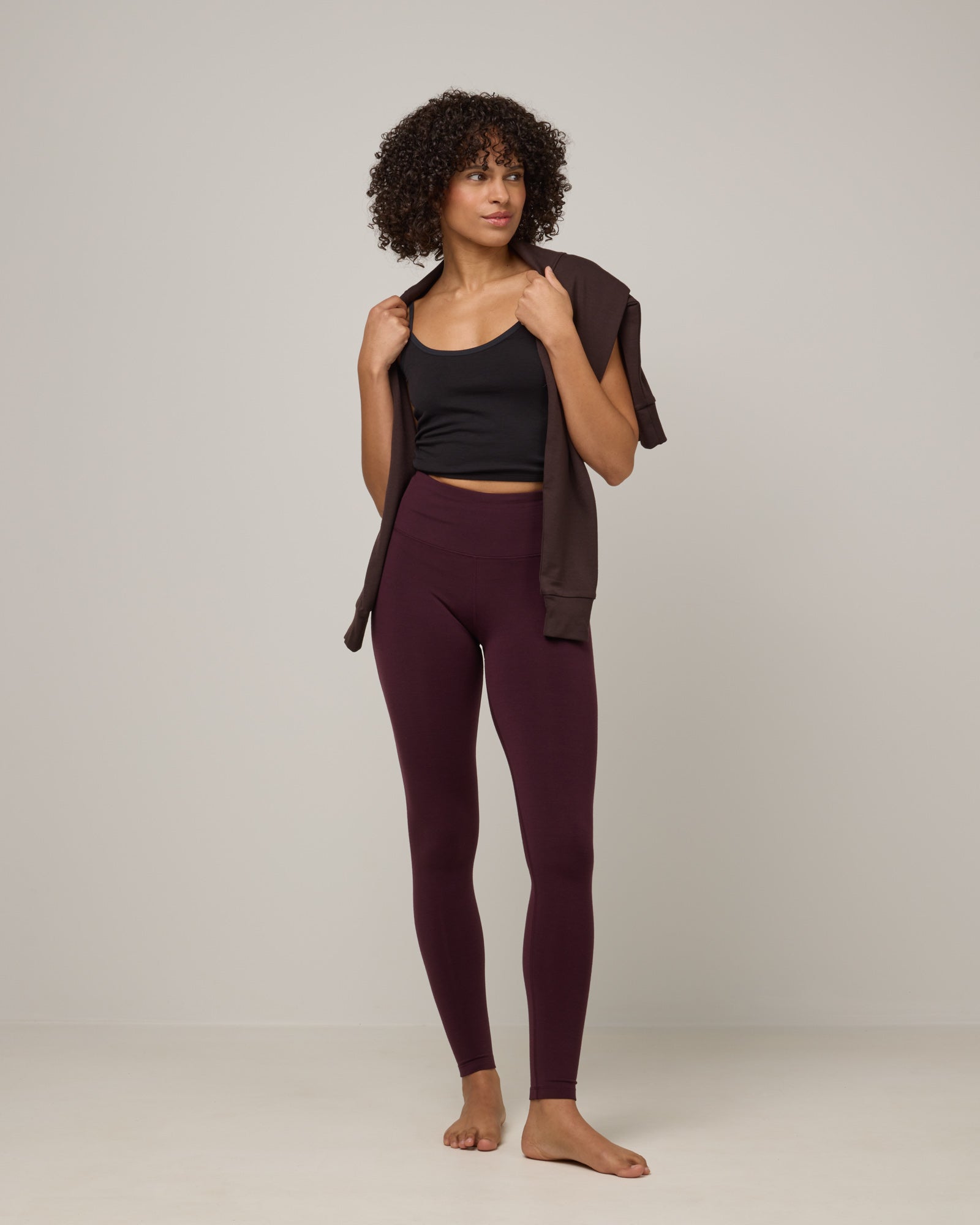 Model wearing Summit Legging in Dark Marionberry, a deep berry purple color. Summit Legging is a merino wool legging available in sizes XS-3X Regular, S-XXL Long.