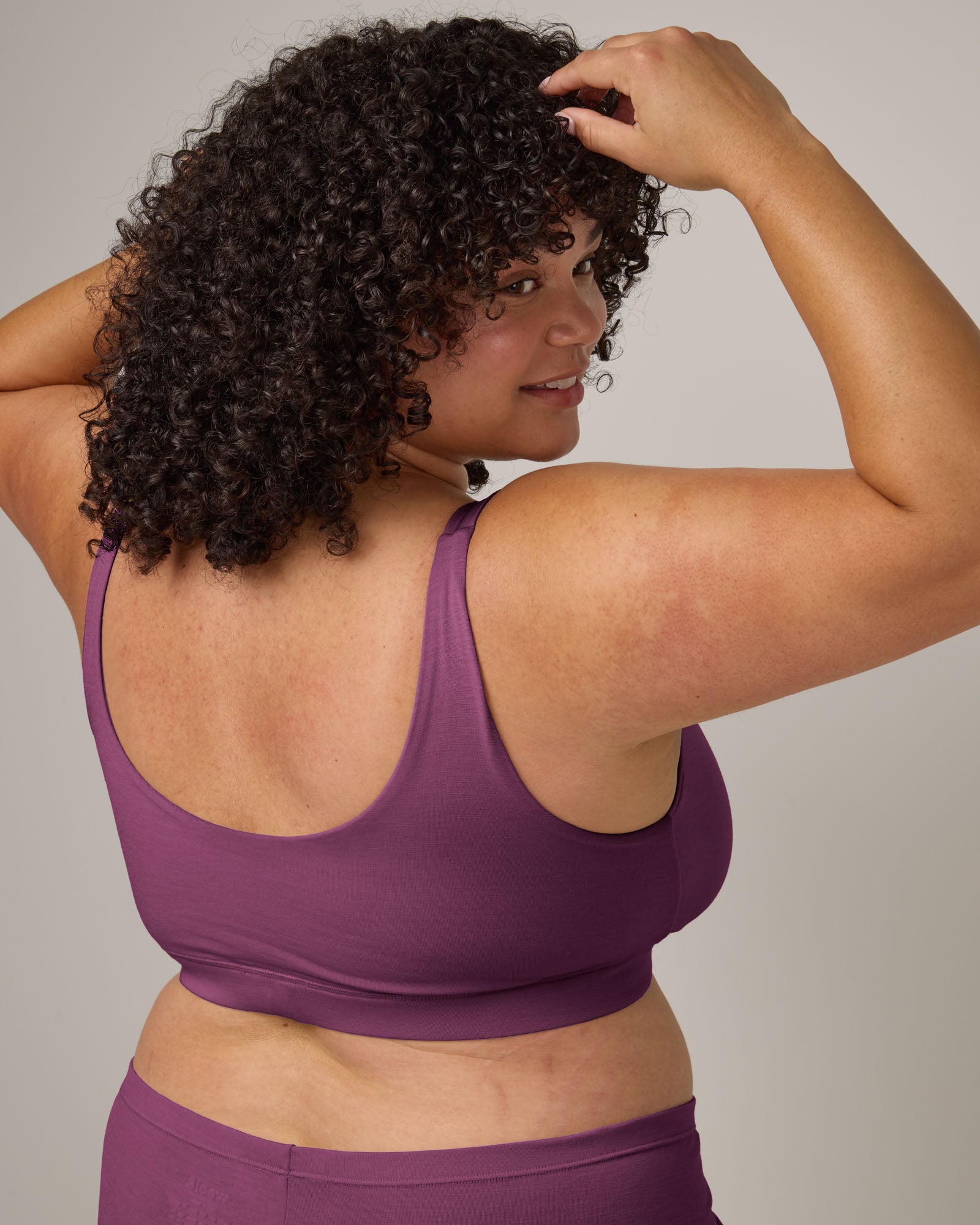 Model wearing Roam Wrap Bra in Plum, a berry pink-purple color. Roam Wrap Bra is a merino wool underwear available in sizes 1X-3X.
