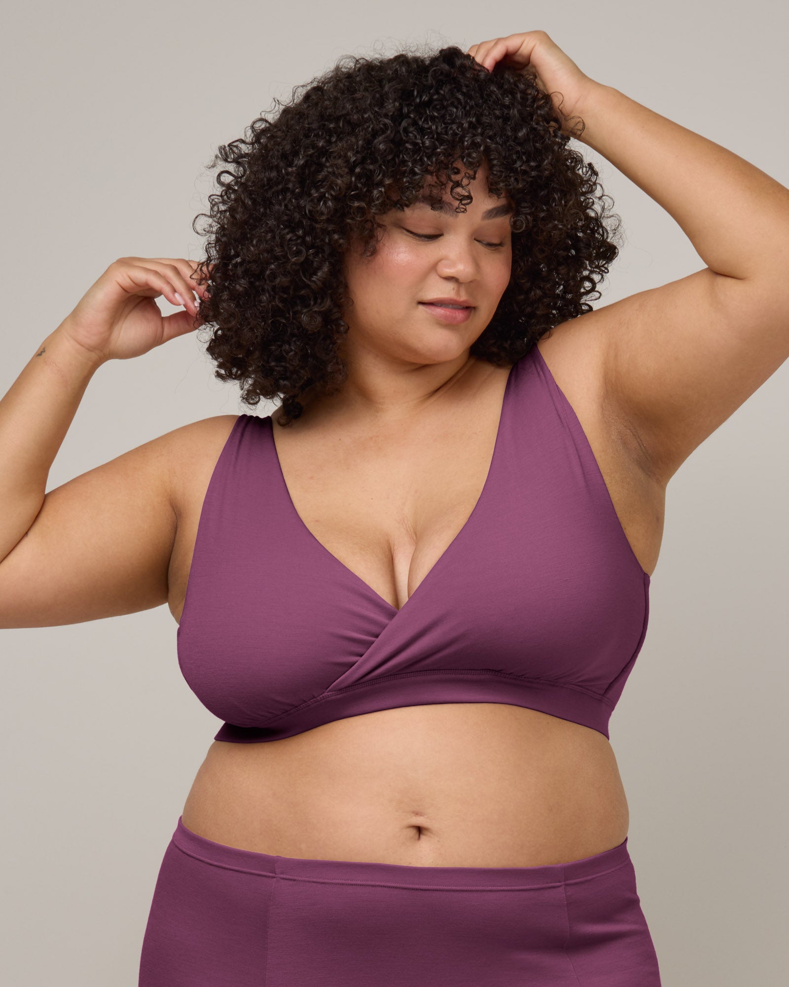 Model wearing Roam Wrap Bra in Plum, a berry pink-purple color. Roam Wrap Bra is a merino wool underwear available in sizes 1X-3X.