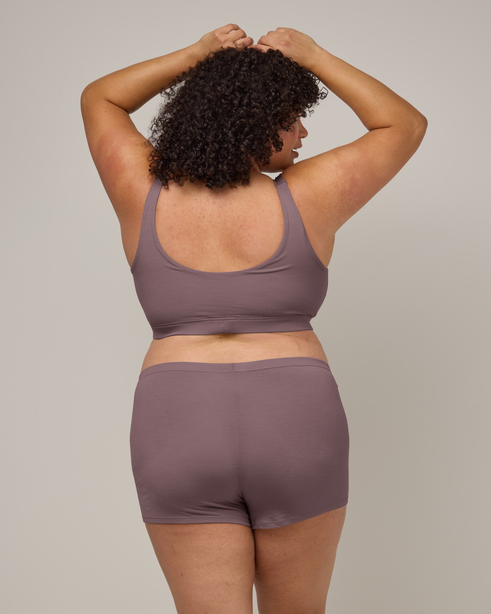 Model wearing Roam Wrap Bra in Lavender, a dusky muted purple color. Roam Wrap Bra is a merino wool underwear item available in sizes 1X-3X.
