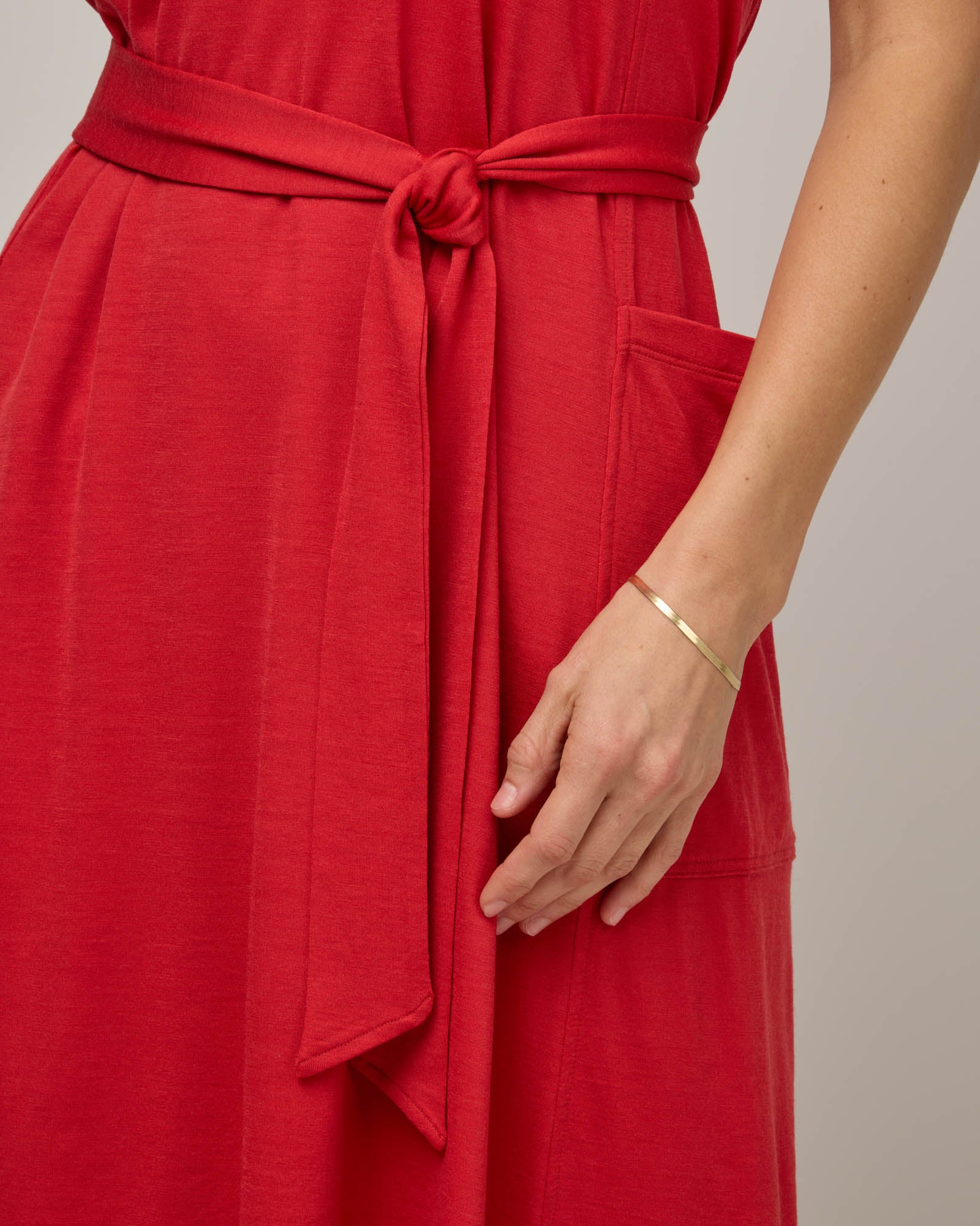 Model wearing Summer Reversible Dress in Fruit Punch, a vivid red-orange color. Summer Reversible Dress is a merino wool sleeveless, reversible, midi swing dress with pockets available in sizes XS-3X.