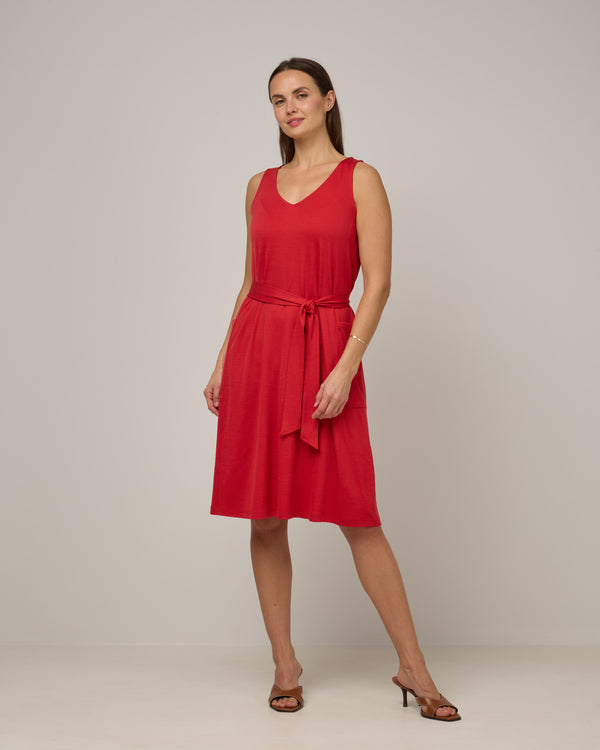 Model wearing Summer Reversible Dress in Fruit Punch, a vivid red-orange color. Summer Reversible Dress is a merino wool sleeveless, reversible, midi swing dress with pockets available in sizes XS-3X.