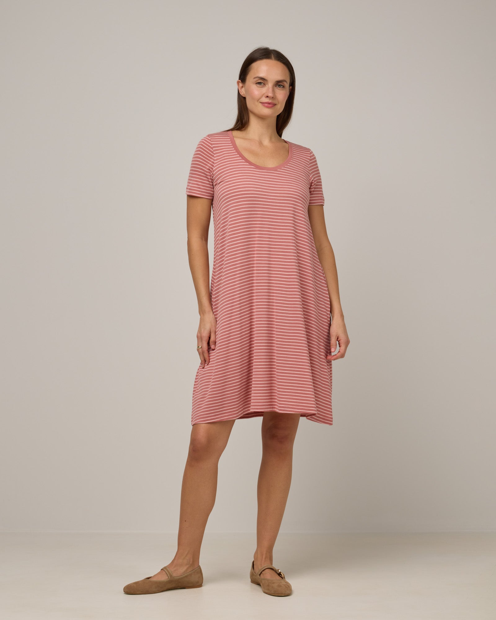Model wearing Maggie Swing Dress in Vintage Rose & Blush Pink Stripe. Maggie Swing Dress is a merino wool short sleeve, scoop neck, knee length swing dress with pockets available in sizes XS-3X Regular, XS-3X Long.