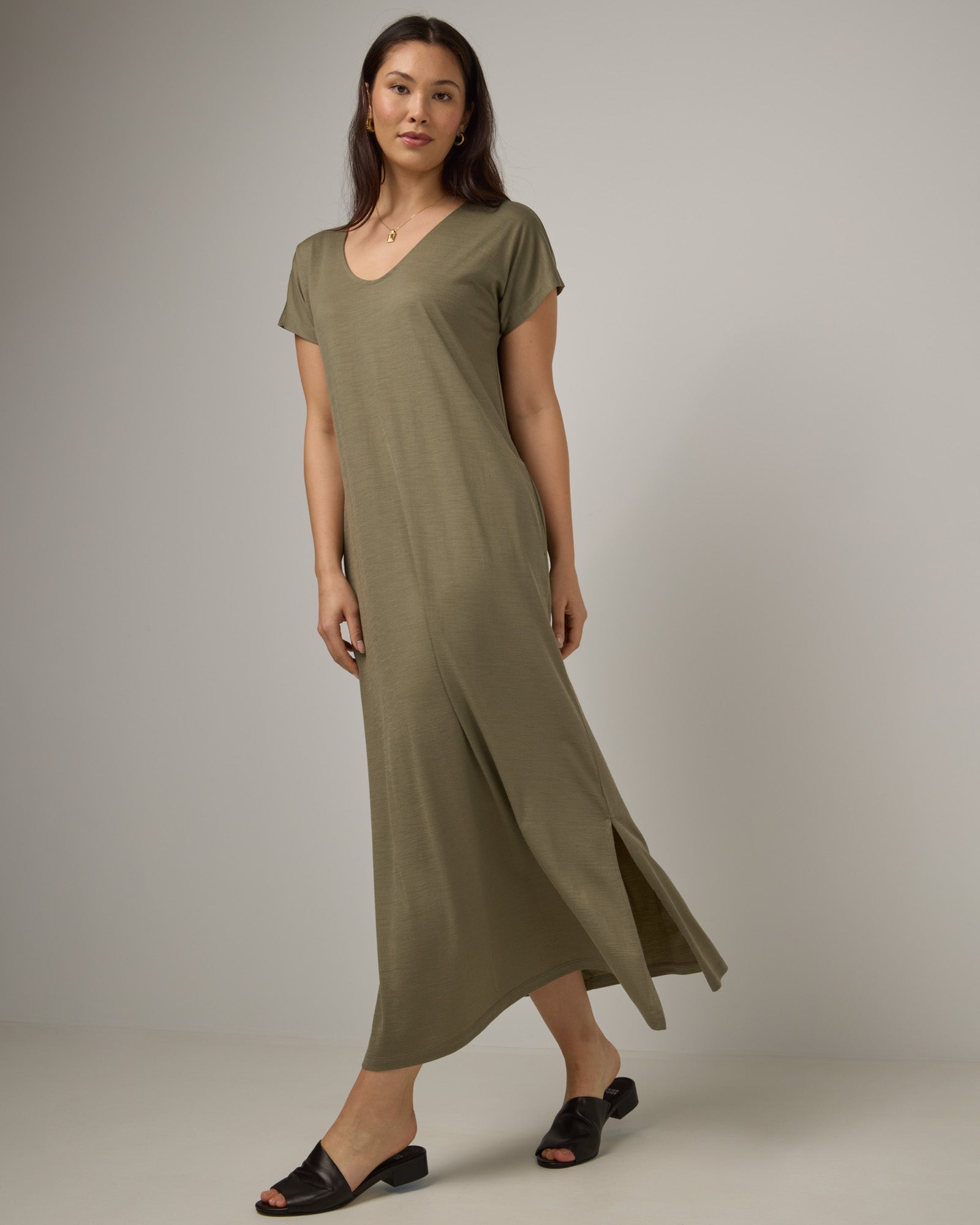 Model wearing Freya Maxi Dress in Sage Green, a soft muted green color. Freya Maxi Dress is a merino wool short sleeve, v-neck, maxi swing dress with pockets available in sizes XS-3X.