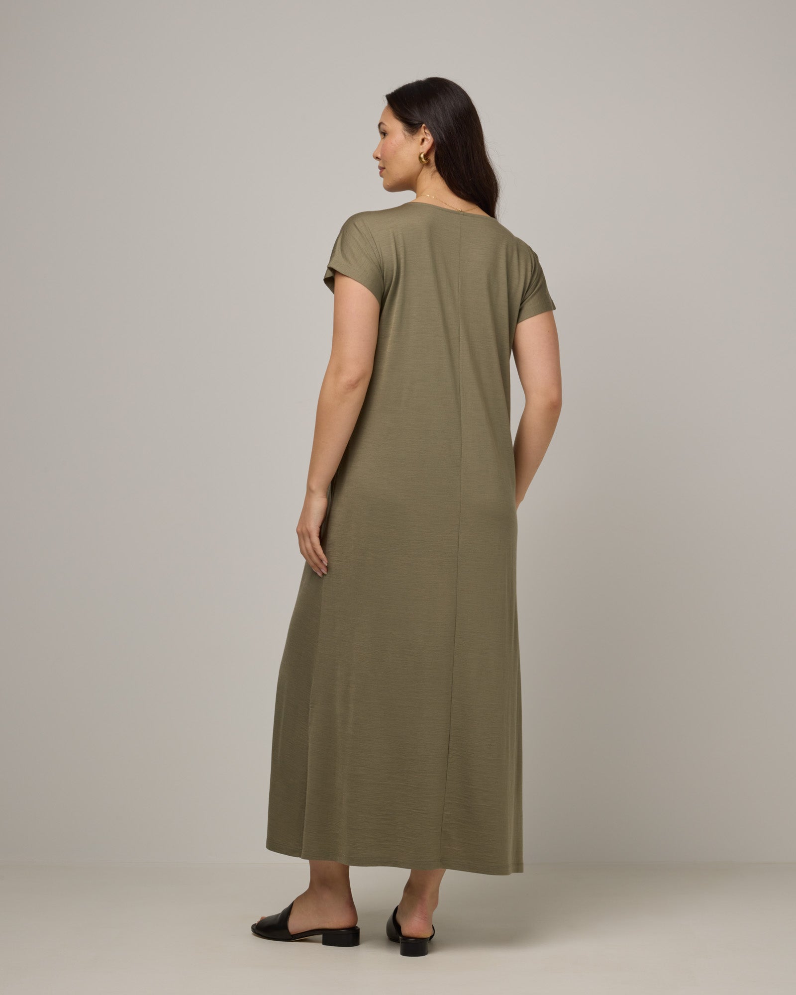 Model wearing Freya Maxi Dress in Sage Green, a soft muted green color. Freya Maxi Dress is a merino wool short sleeve, v-neck, maxi swing dress with pockets available in sizes XS-3X.