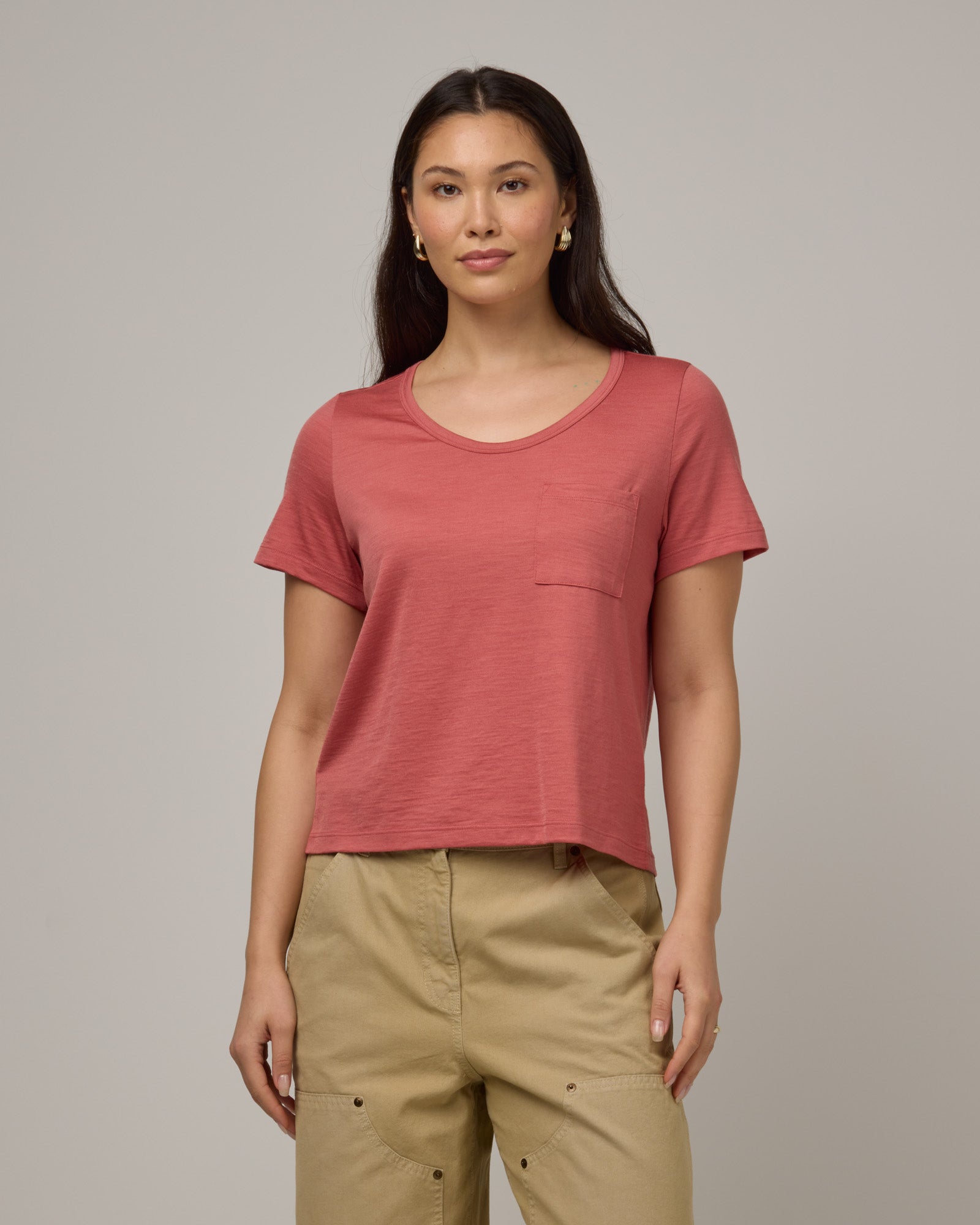 Model wearing Hailee Boxy Tee in Dusty Cedar, a soft pink-coral color. Hailee Boxy Tee is a merino wool short sleeve, crew neck, relaxed fit tee available in sizes XS-3X.