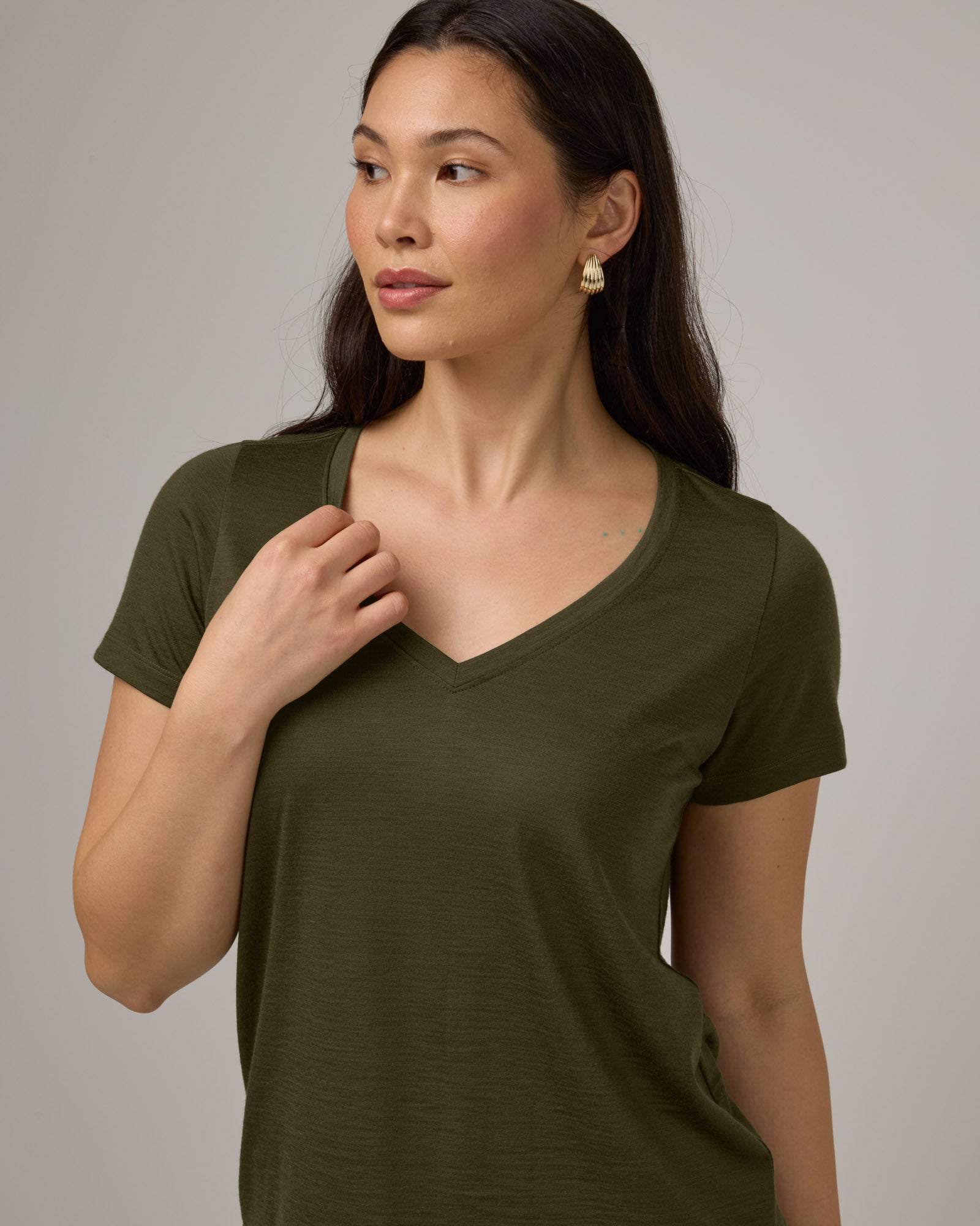 Model wearing Morgan V-Neck Tee in Forest Night, a muted dark green color. Morgan V-Neck Tee is a merino wool short sleeve, v-neck, regular fit tee available in sizes XS-3X.