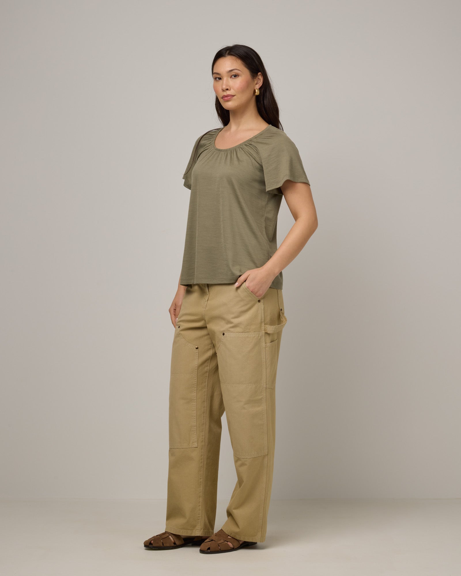 Model wearing Lilah Signature Gathered Neck Tee in Sage Green, a soft muted green color. Lilah Signature Gathered Neck Tee is a merino wool short sleeve, scoop neck, relaxed fit tee available in sizes XS-3X.