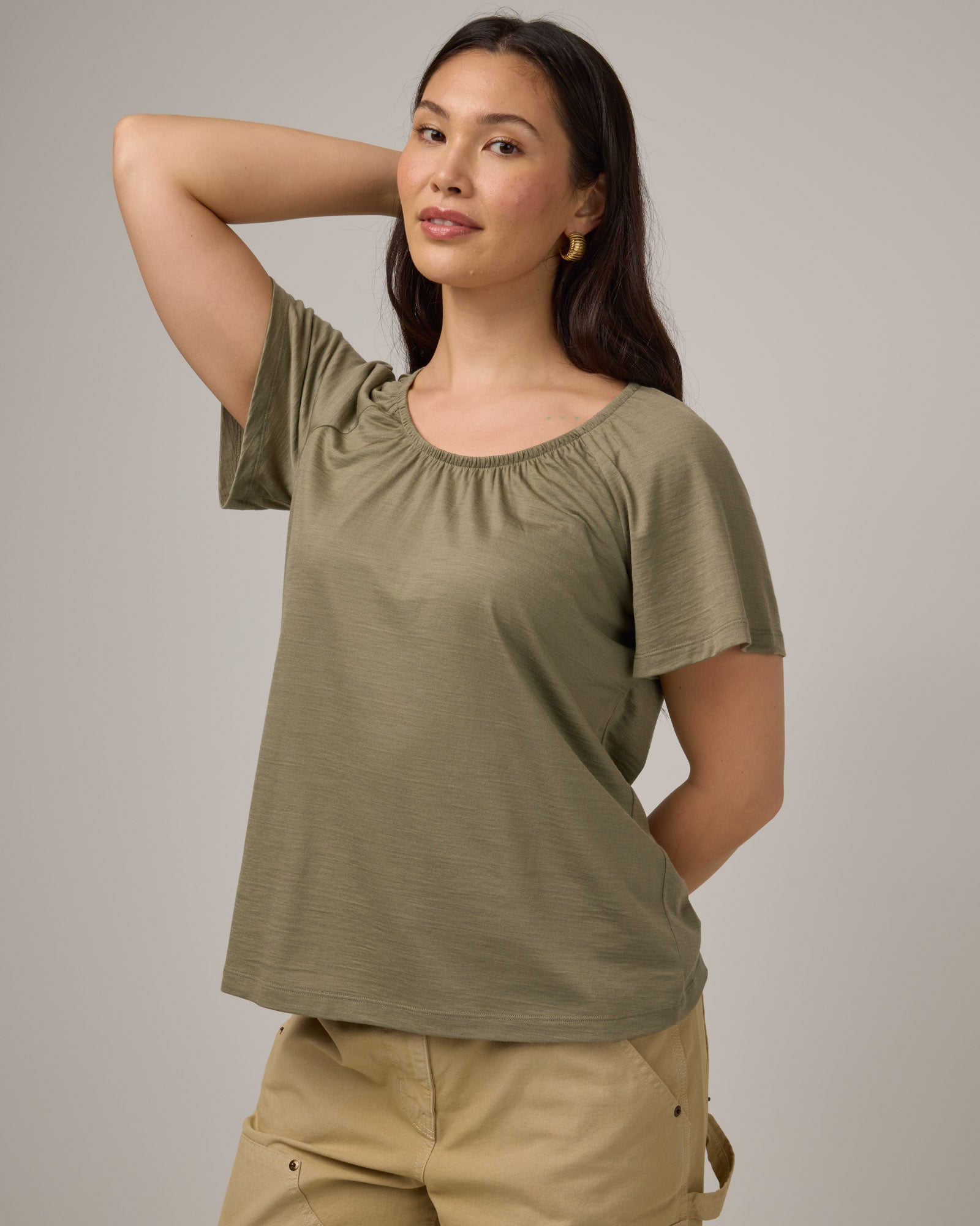 Model wearing Lilah Signature Gathered Neck Tee in Sage Green, a soft muted green color. Lilah Signature Gathered Neck Tee is a merino wool short sleeve, scoop neck, relaxed fit tee available in sizes XS-3X.