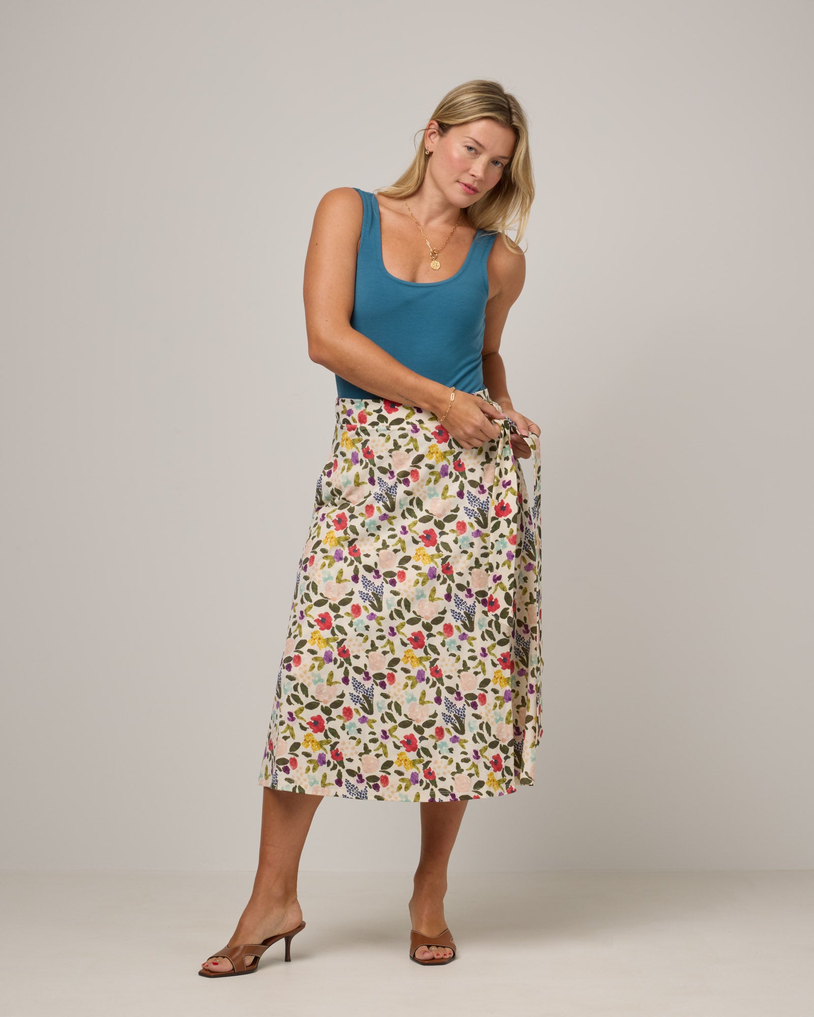 Model wearing Skye Wrap Skirt in Watercolor Floral, a multi-colored floral print on a cream background. Skye Wrap Skirt is a merino wool skirt with pockets available in sizes XS-3X.