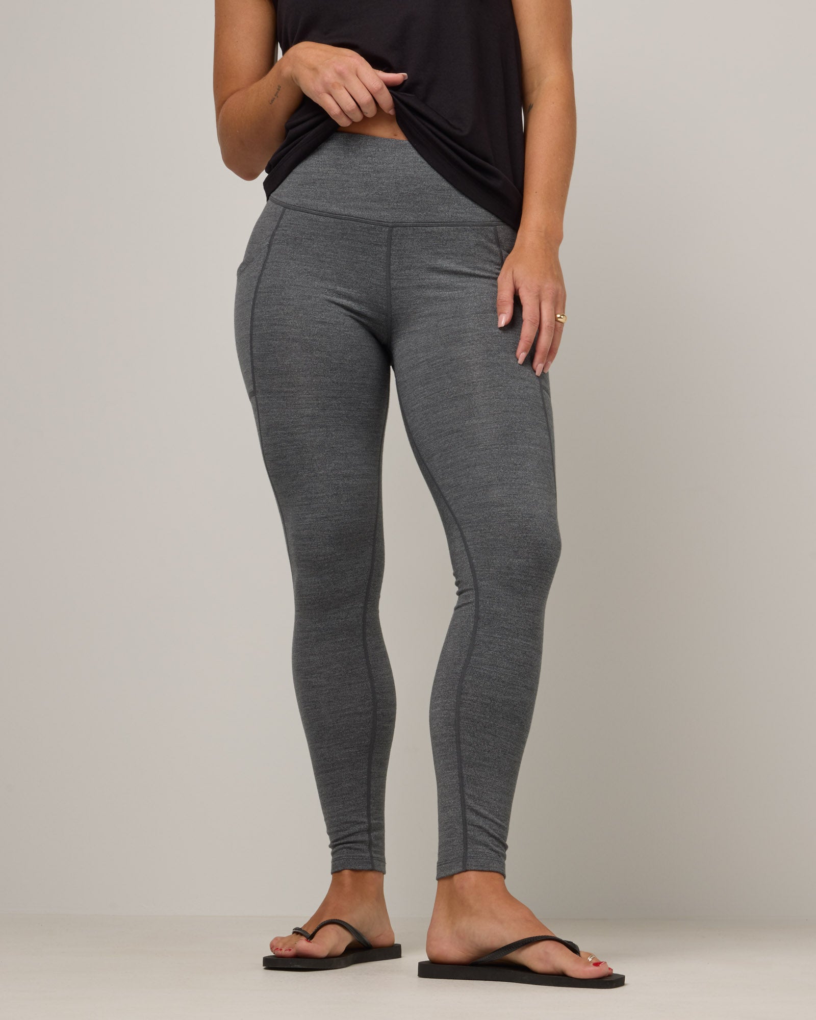 Model wearing Summit Pocket Legging in Charcoal Heather, a dark heather gray color. Summit Pocket Legging is a merino wool legging with pockets available in sizes XS-3X.