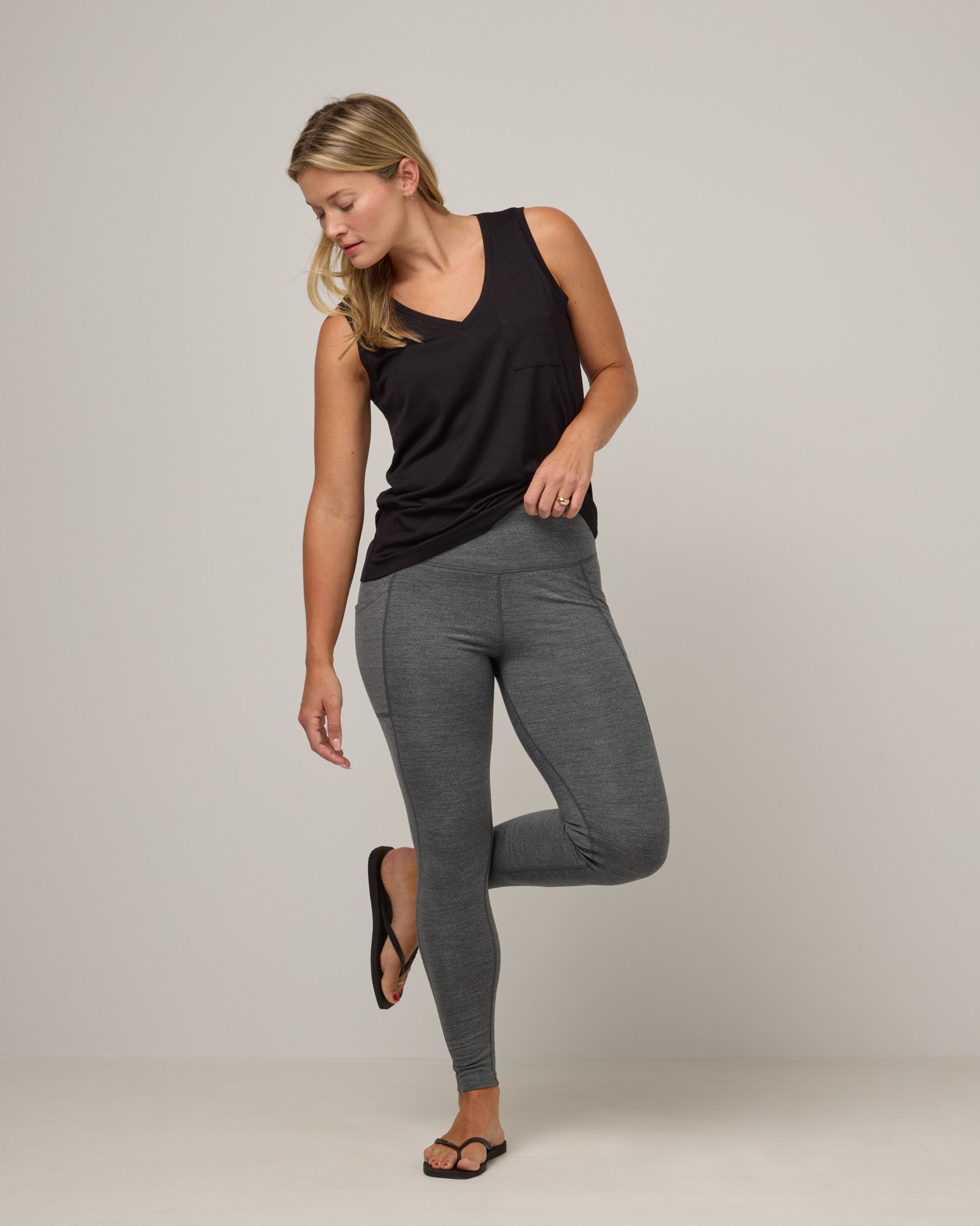 Model wearing Summit Pocket Legging in Charcoal Heather, a dark heather gray color. Summit Pocket Legging is a merino wool legging with pockets available in sizes XS-3X.