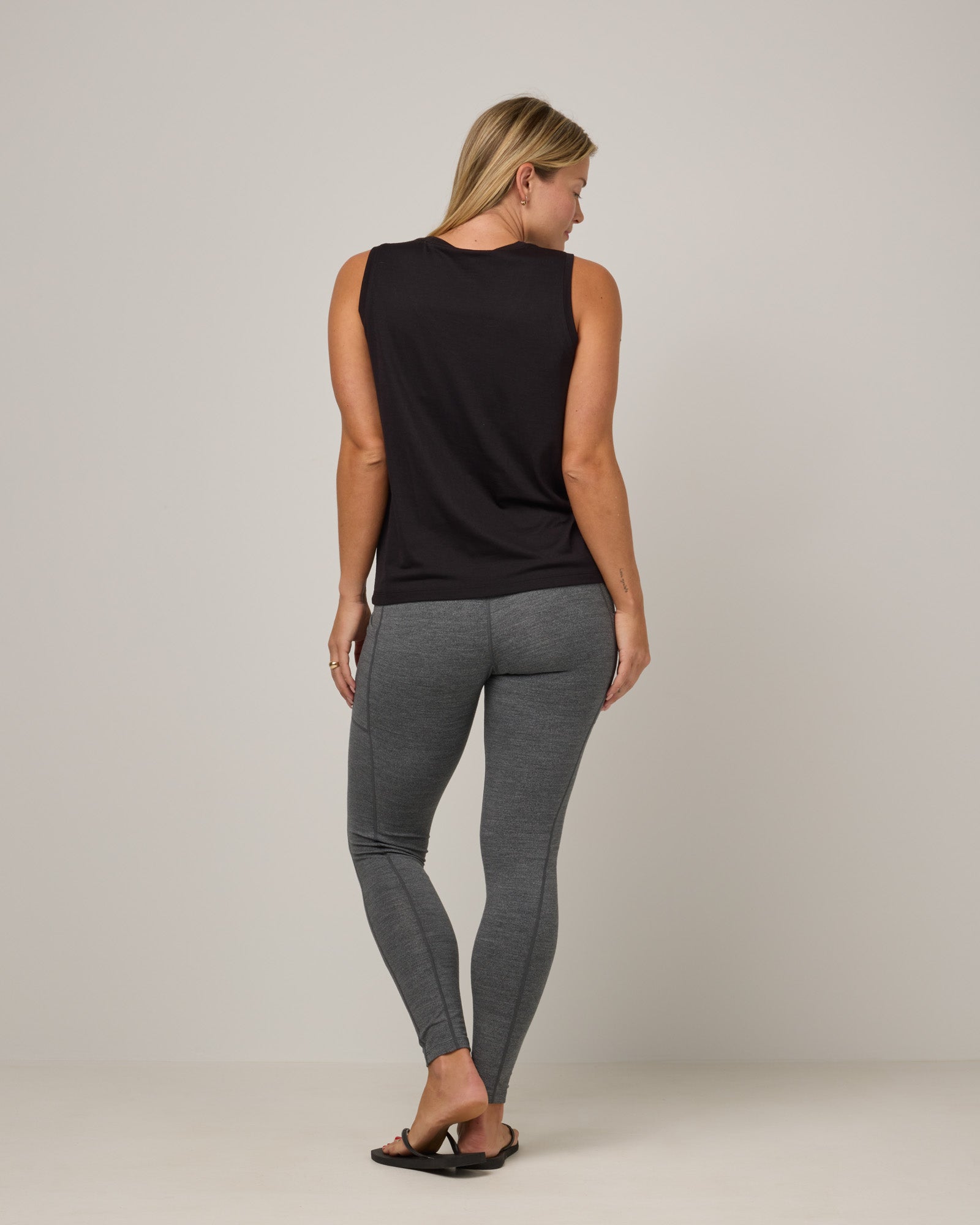 Model wearing Summit Pocket Legging in Charcoal Heather, a dark heather gray color. Summit Pocket Legging is a merino wool legging with pockets available in sizes XS-3X.