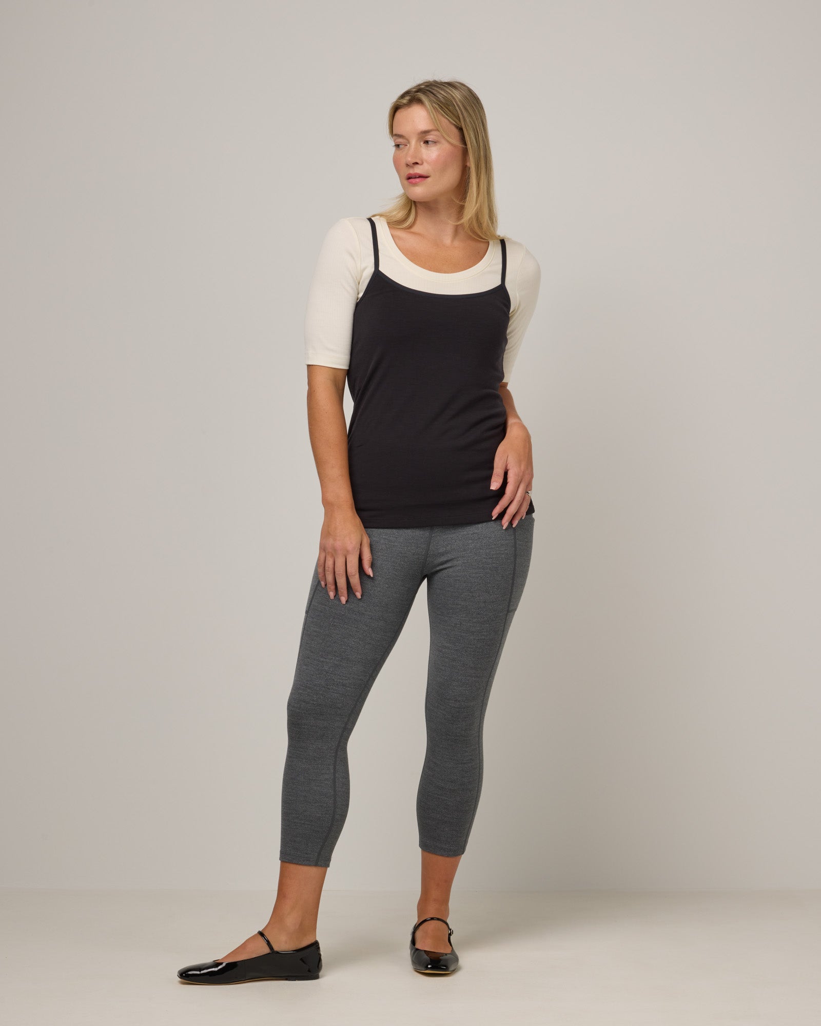 Model wearing Summit Pocket Crop Legging in Charcoal Heather, a dark heather gray color. Summit Pocket Crop Legging is a merino wool legging with pockets available in sizes XS-3X.