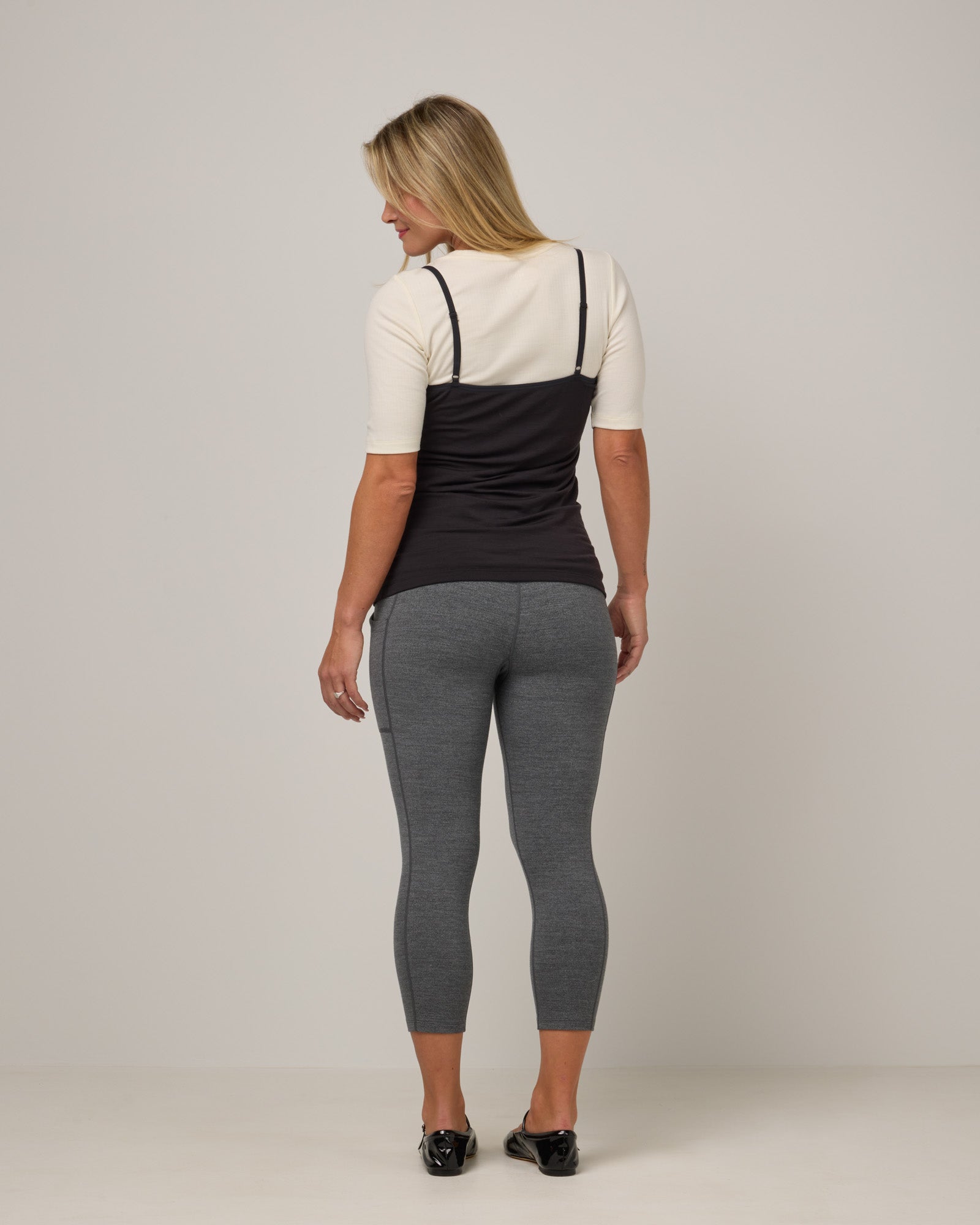 Model wearing Summit Pocket Crop Legging in Charcoal Heather, a dark heather gray color. Summit Pocket Crop Legging is a merino wool legging with pockets available in sizes XS-3X.