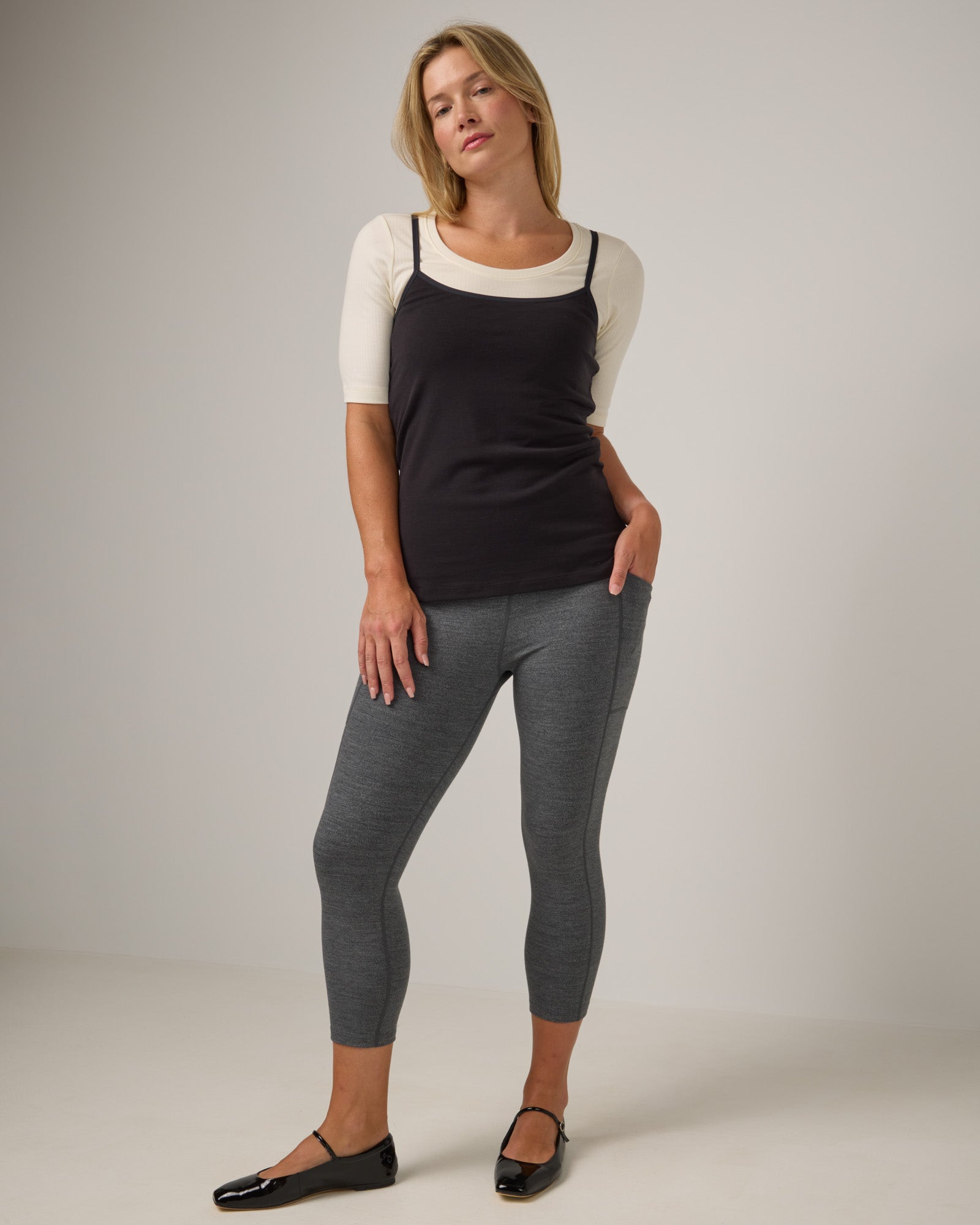 Model wearing Summit Pocket Crop Legging in Charcoal Heather, a dark heather gray color. Summit Pocket Crop Legging is a merino wool legging with pockets available in sizes XS-3X.