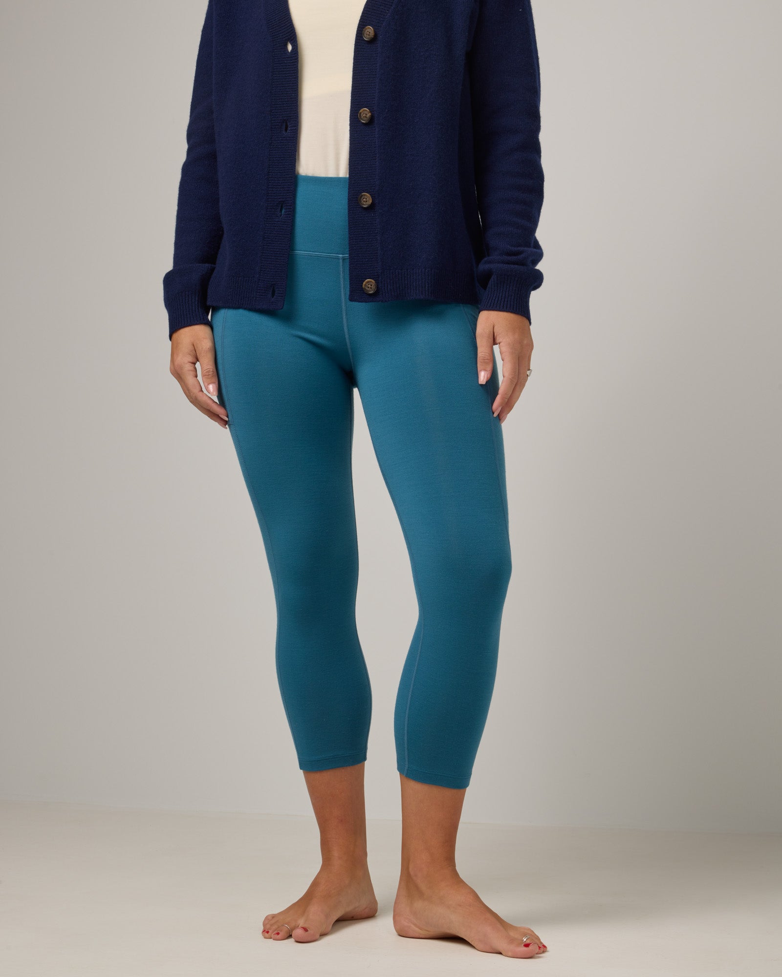 Model wearing Summit Pocket Crop Legging in Ocean Teal, a medium blue-green color. Summit Pocket Crop Legging is a merino wool legging with pockets available in sizes XS-3X.