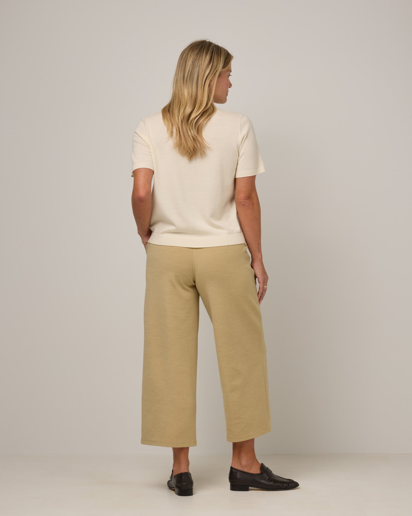 Model wearing Frame Ponte Culotte in Sahara, a warm, sandy tan neutral color. Frame Ponte Culotte is a merino wool pant with pockets available in sizes XS-3X Regular, XS-XL Petite.