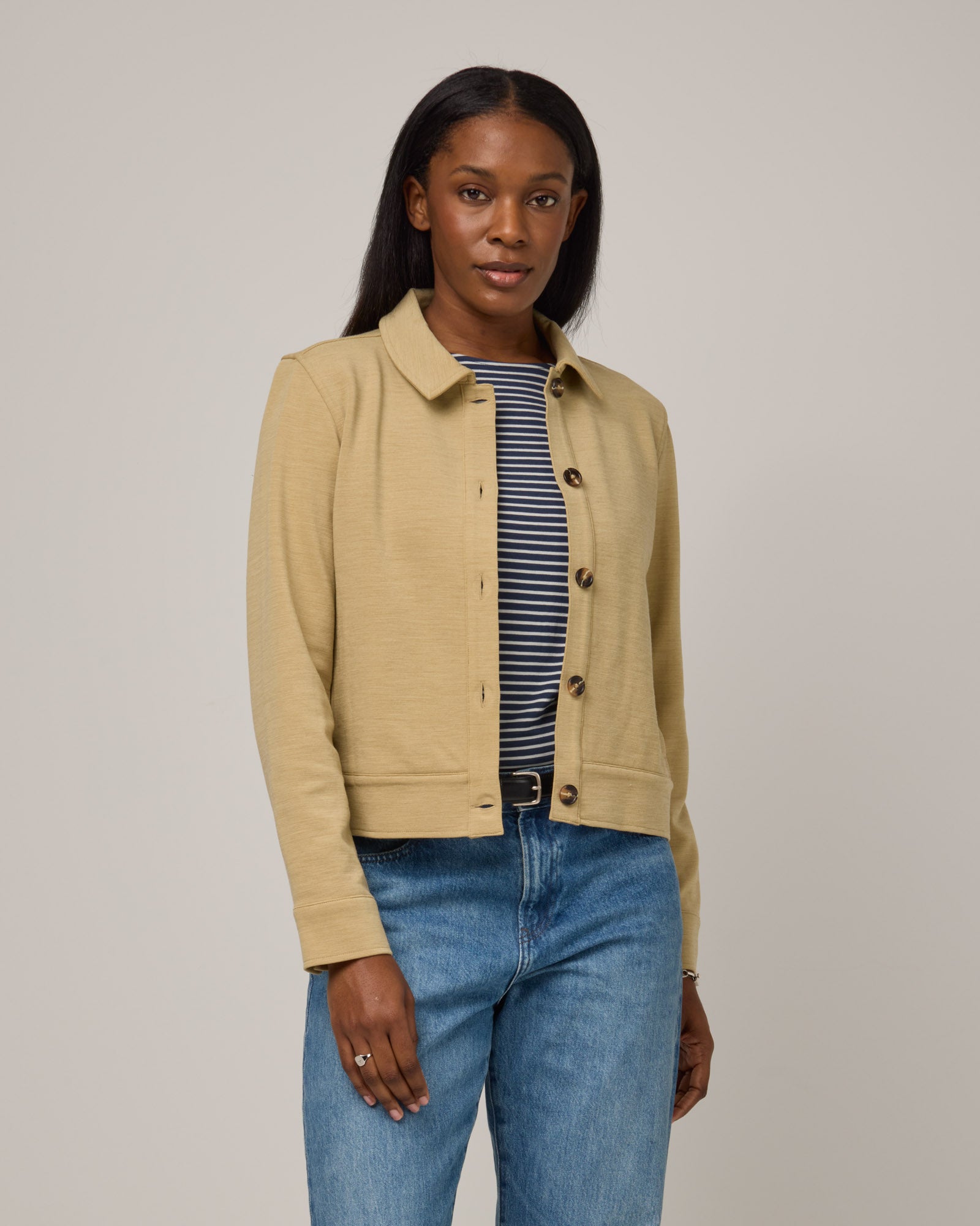 Model wearing Johnny Ponte Jacket in Sahara, a warm, sandy tan neutral color. Johnny Ponte Jacket is a merino wool long sleeve, collared, jacket with pockets available in sizes XS-XXL.