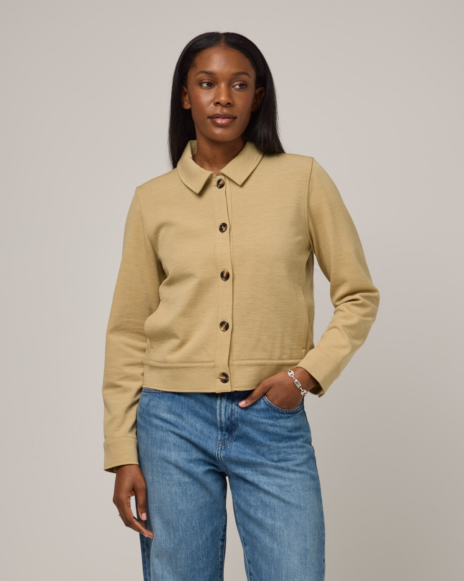 Model wearing Johnny Ponte Jacket in Sahara, a warm, sandy tan neutral color. Johnny Ponte Jacket is a merino wool long sleeve, collared, jacket with pockets available in sizes XS-XXL.