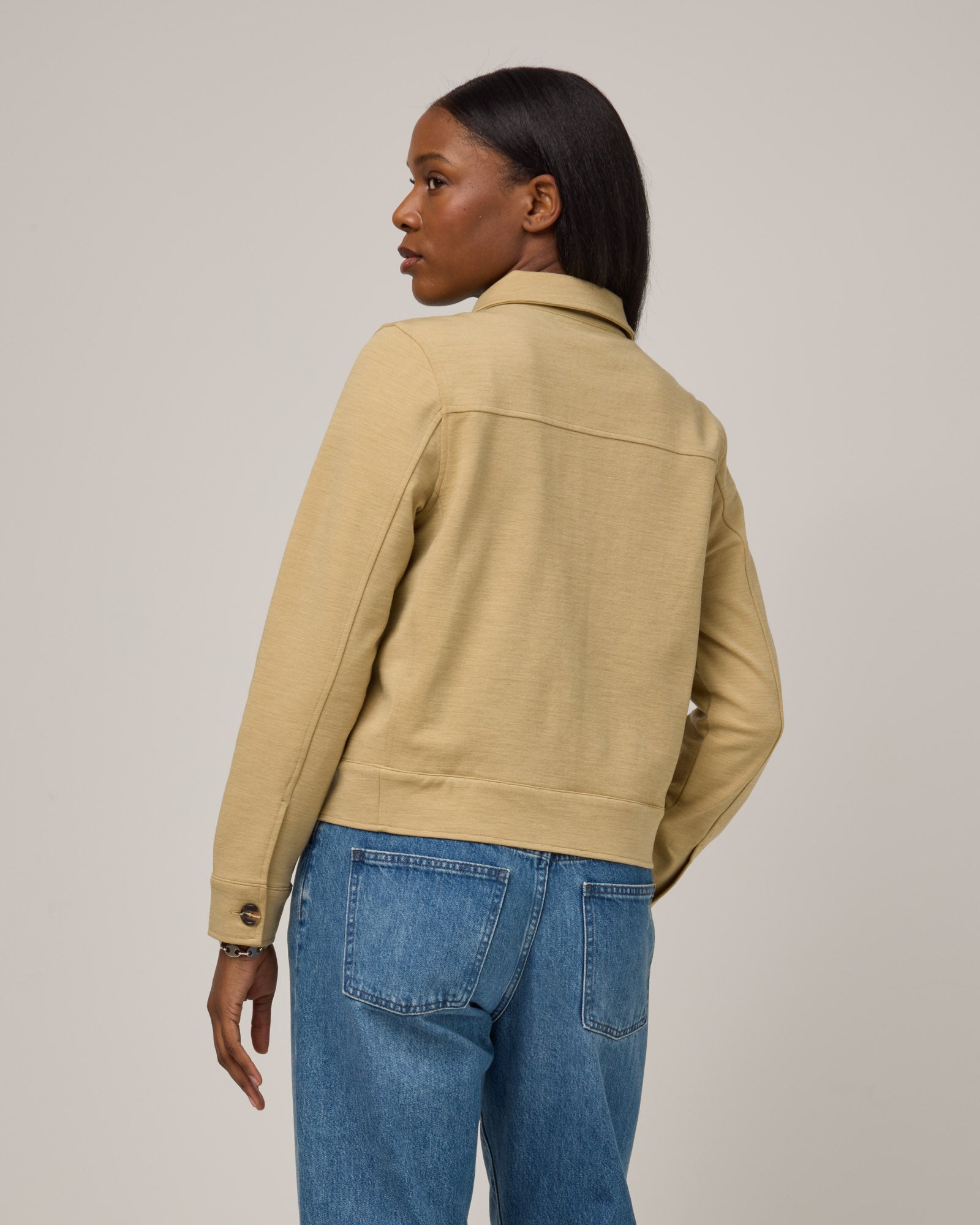 Model wearing Johnny Ponte Jacket in Sahara, a warm, sandy tan neutral color. Johnny Ponte Jacket is a merino wool long sleeve, collared, jacket with pockets available in sizes XS-XXL.