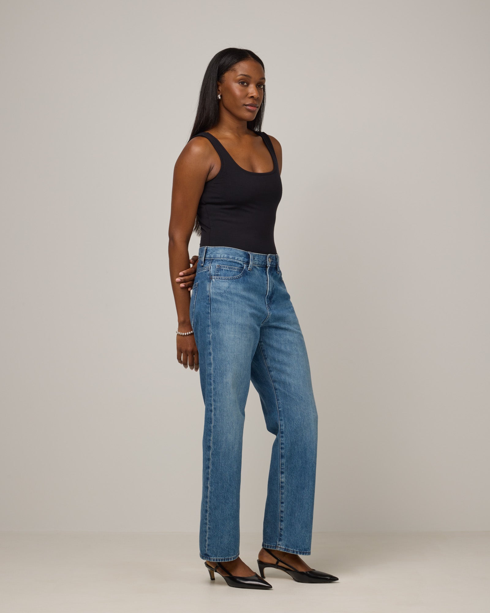 Model wearing Britt Bodysuit in Black. Britt Bodysuit is a merino wool slim fit, sleeveless, scoop neck bodysuit available in sizes XS-XXL.