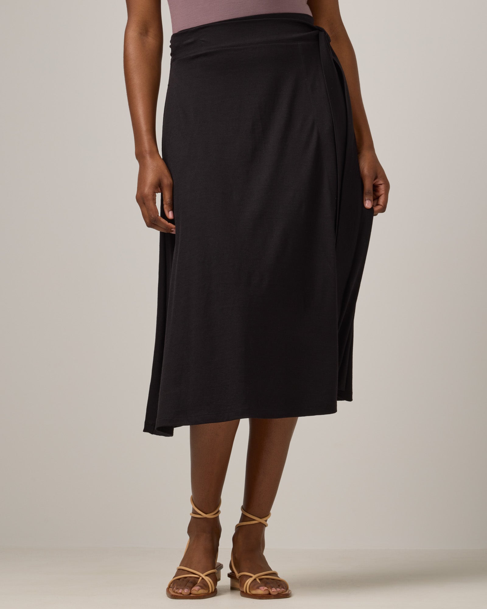 Model wearing Skye Wrap Skirt in Black. Skye Wrap Skirt is a merino wool midi length skirt with pockets available in sizes XS-3X.