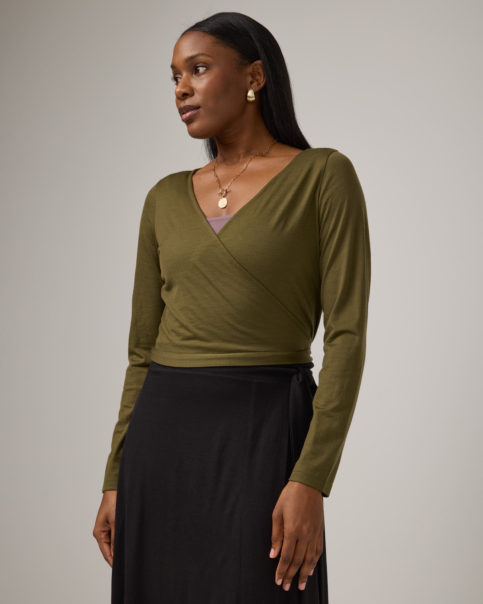 Model wearing Natalia Wrap Top in Olive. Natalia Wrap Top is a merino wool long sleeve, v-neck, slim fit top available in sizes XS-3X.