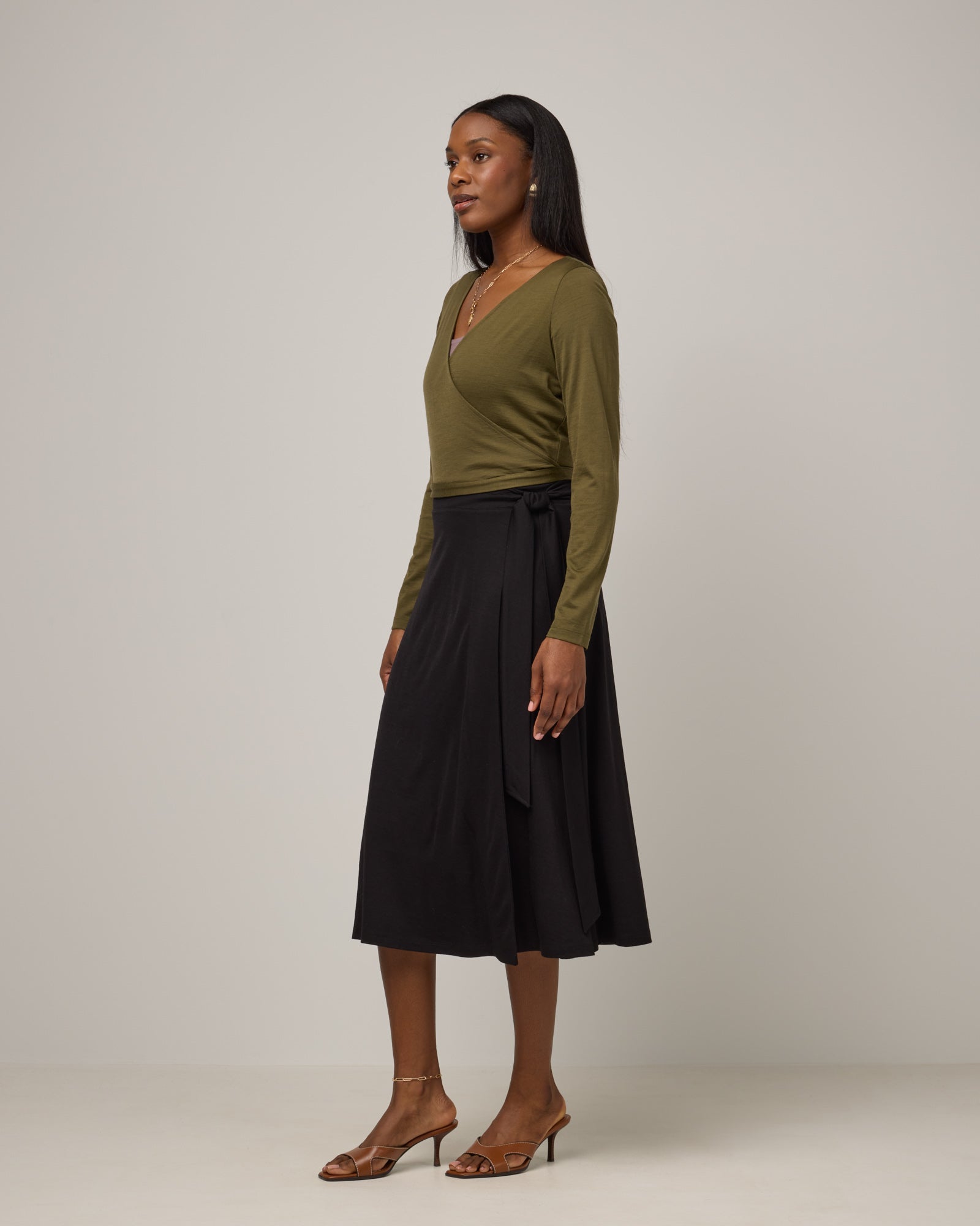 Model wearing Natalia Wrap Top in Olive. Natalia Wrap Top is a merino wool long sleeve, v-neck, slim fit top available in sizes XS-3X.
