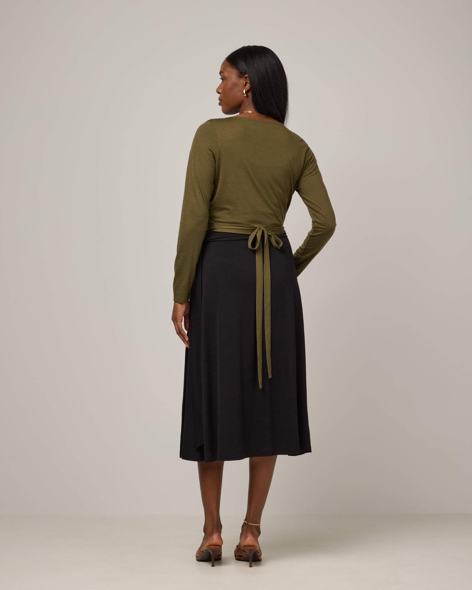 Model wearing Natalia Wrap Top in Olive. Natalia Wrap Top is a merino wool long sleeve, v-neck, slim fit top available in sizes XS-3X.